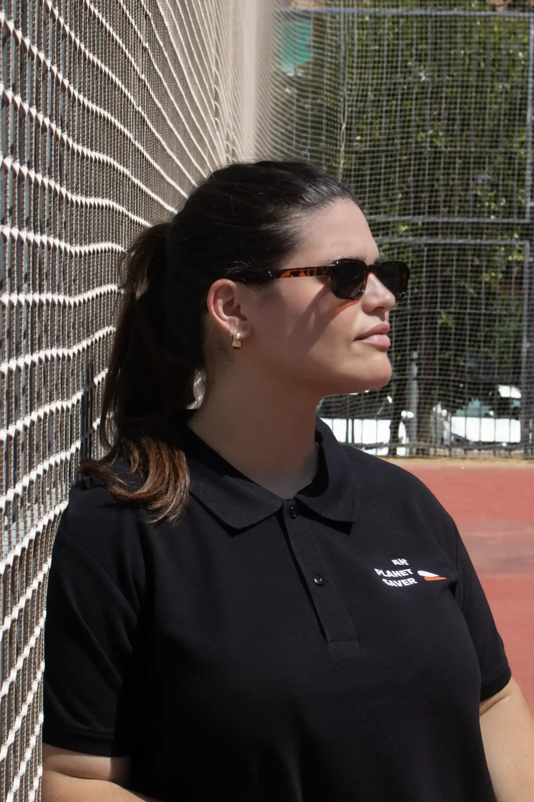 Polo algodón negro personalizado modelo chica con gafas de sol en pista de tenis