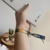 Mano llevando una pulsera reciclada en rPET personalizada y sujetando un cuaderno blanco