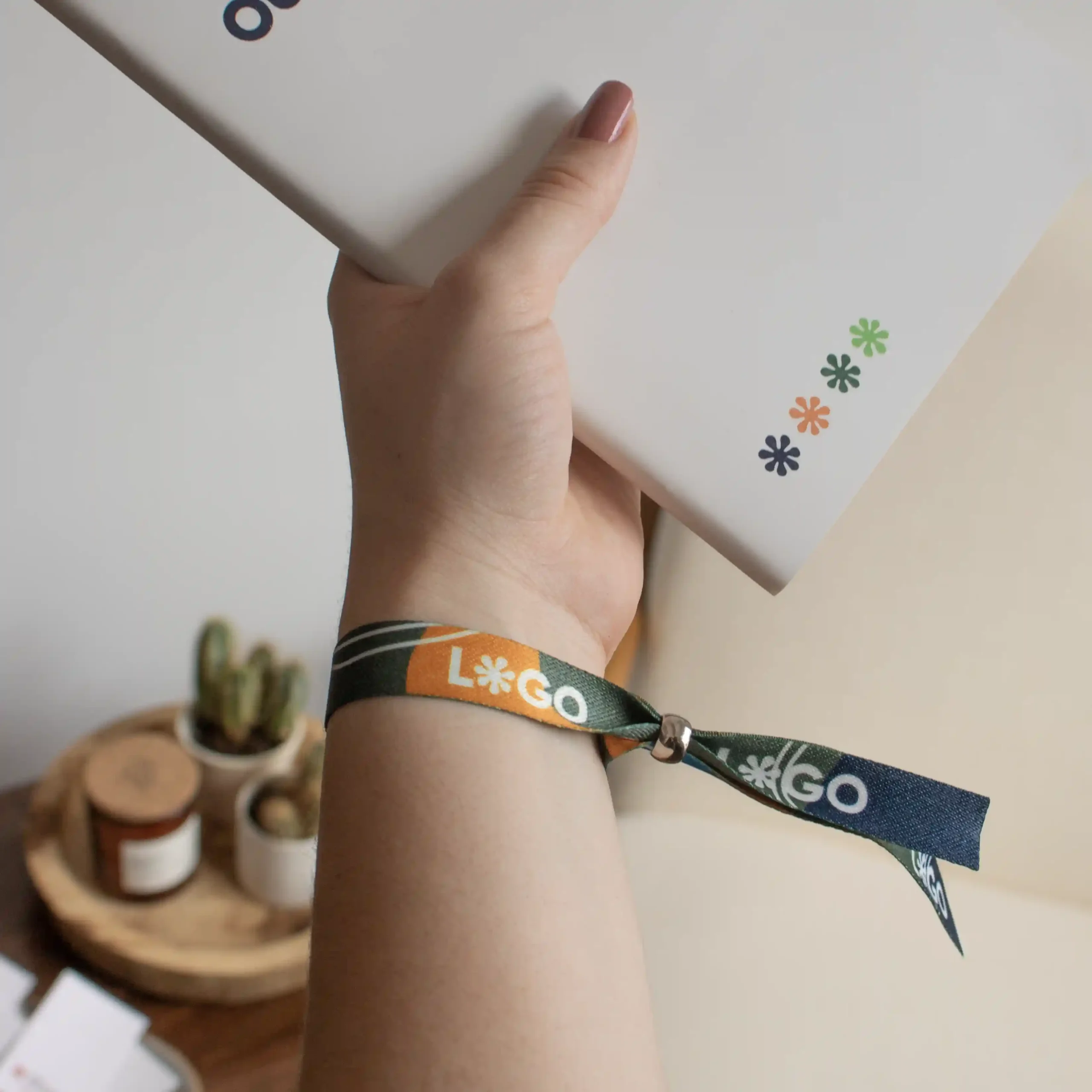 Mano llevando una pulsera reciclada en rPET personalizada y sujetando un cuaderno blanco