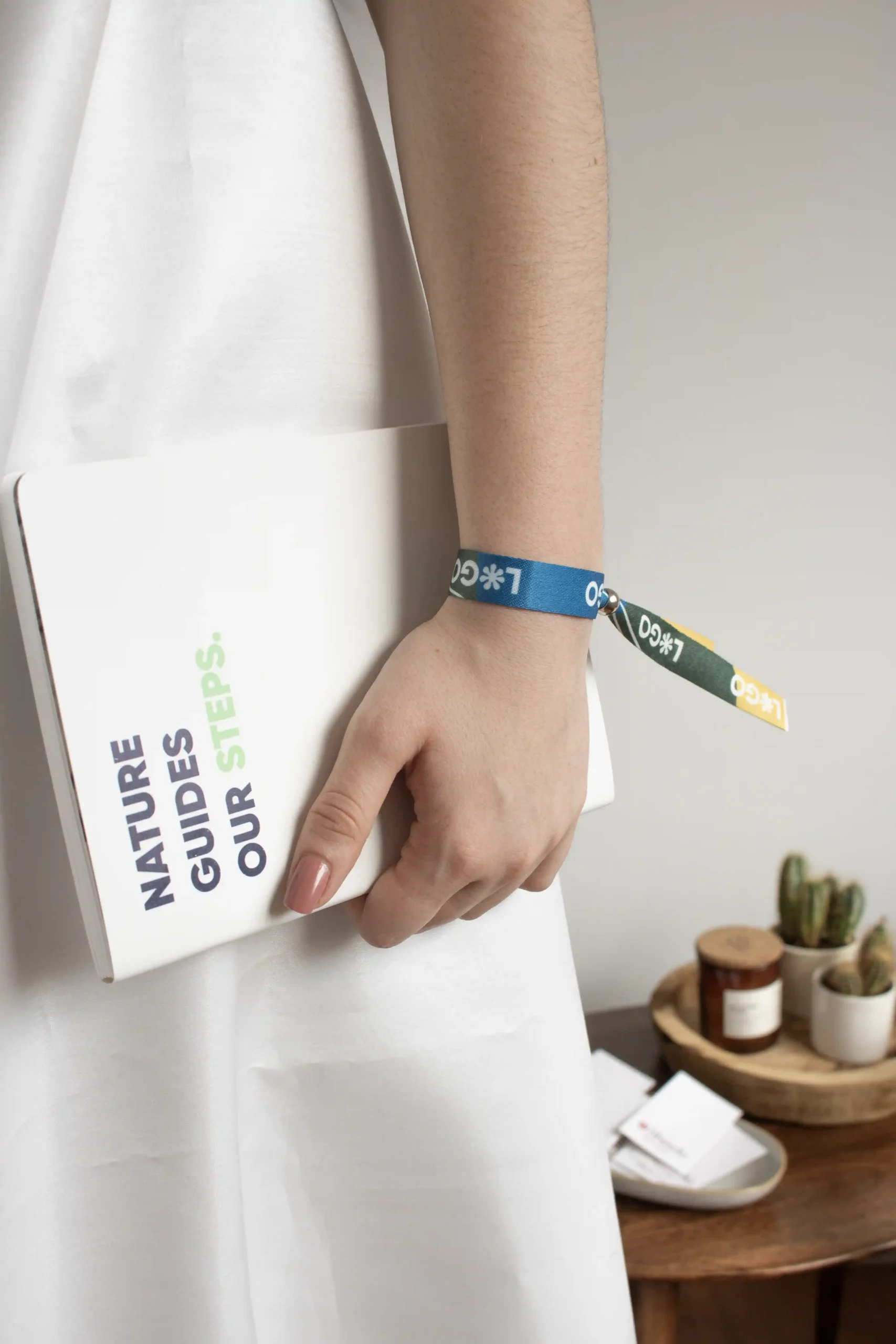 Brazo de chica con pulsera reciclada en rPET personalizada con logo a todo color y cuaderno blanco