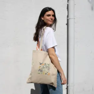 Chica paseando en la calle con bolsa de cáñamo personalizada con logo de colores