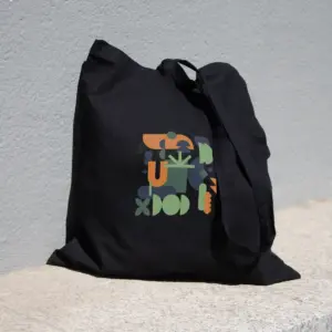 Bolsa negra de algodón orgánico personalizada con logo de colores apoyada en el suelo