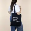 Chica llevando una bolsa negra de algodón orgánico personalizada con logo blanco
