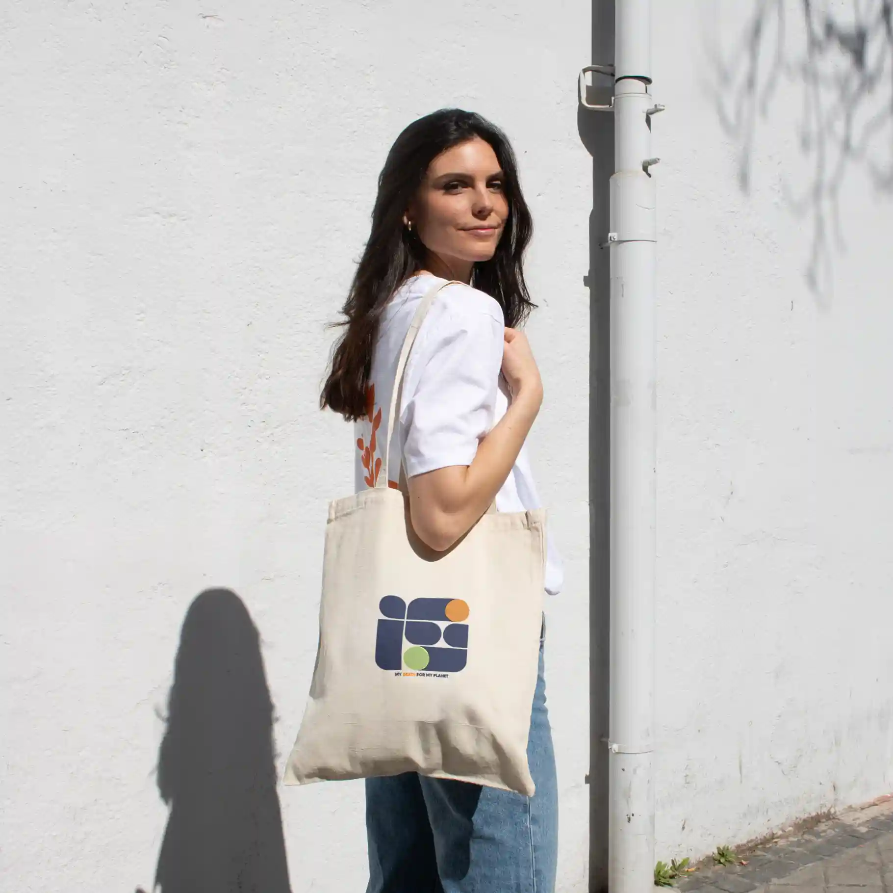 Chica paseando en la calle llevando una bolsa de algodón personalizada con logo de colores
