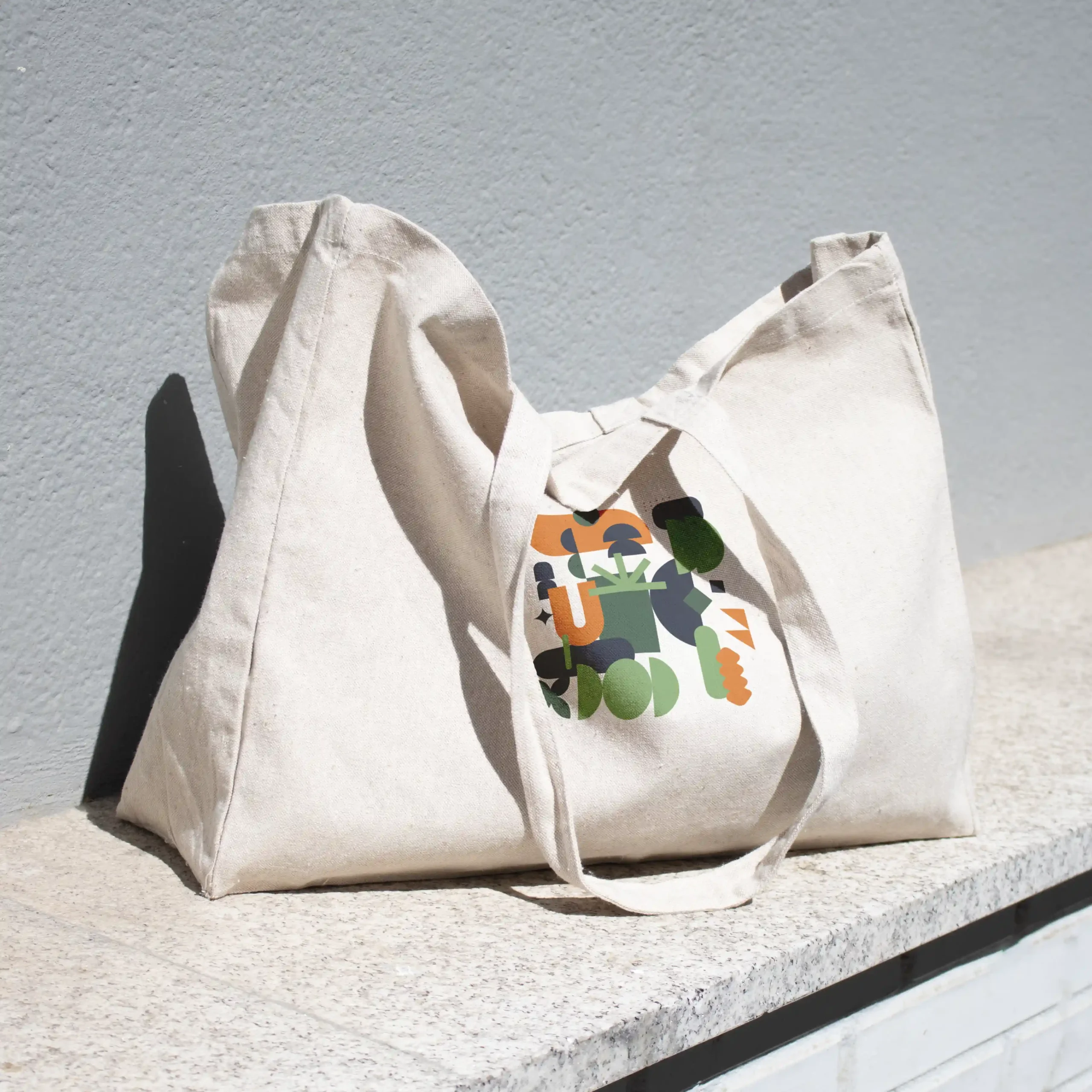 bolsa de algodón reciclado personalizada con logo de colores con fondo pared gris