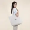 Chica sobre fondo beige con bolsa de algodón reciclado personalizada con logo