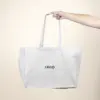 Mano sujetando una bolsa de algodón reciclado personalizada con logo