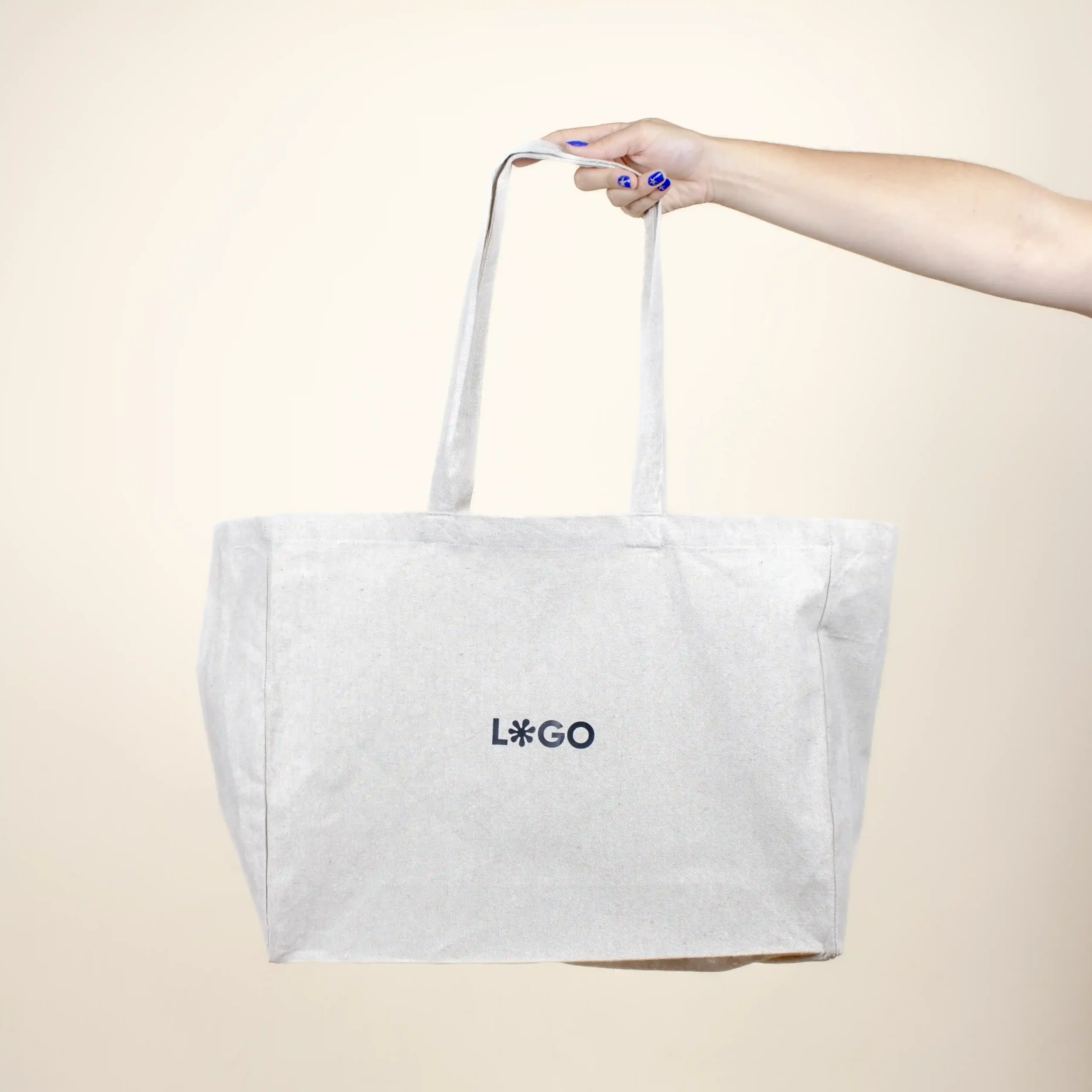 Mano sujetando una bolsa de algodón reciclado personalizada con logo