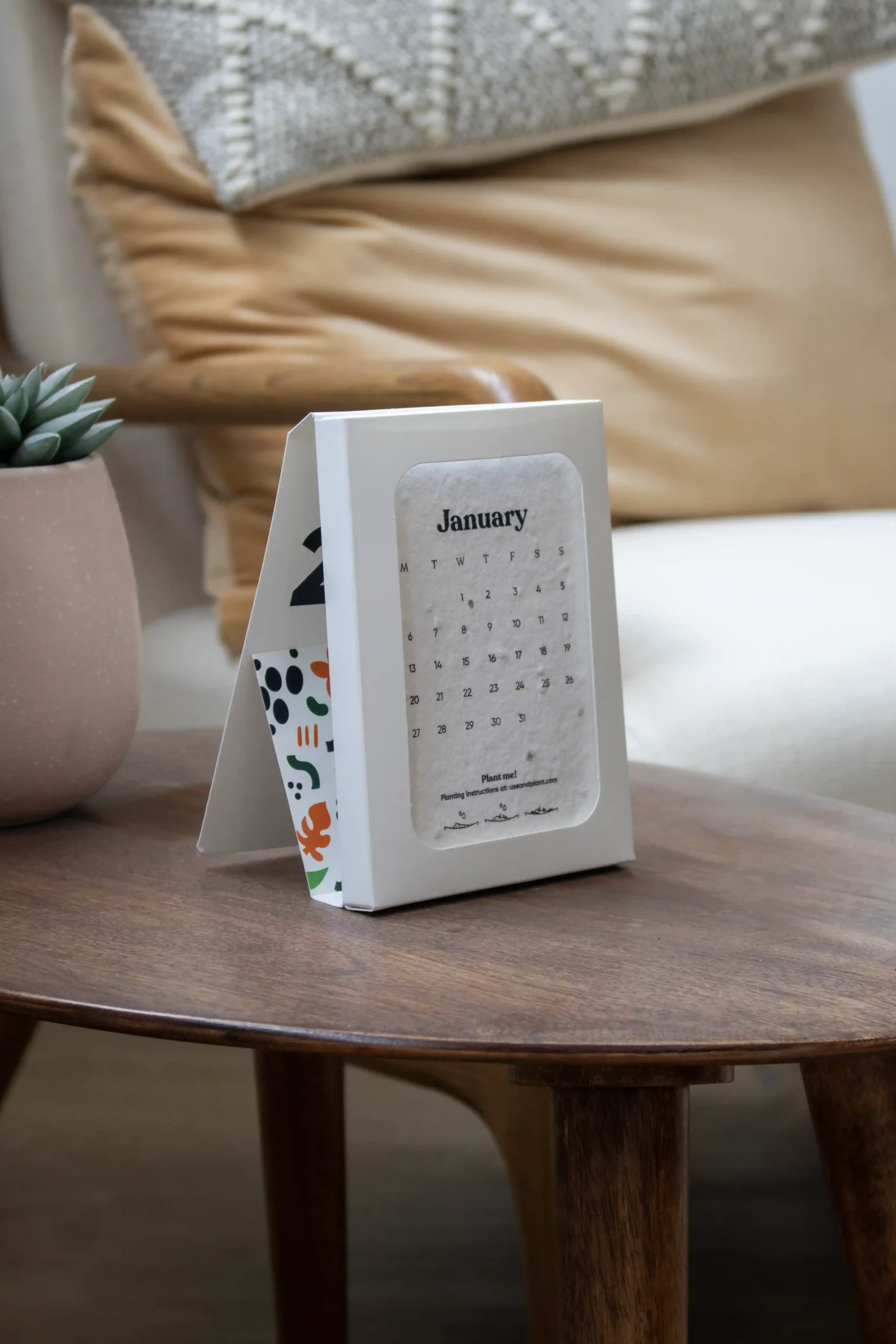 Calendario de semillas en estuche blanco personalizado colocado sobre una mesa madera