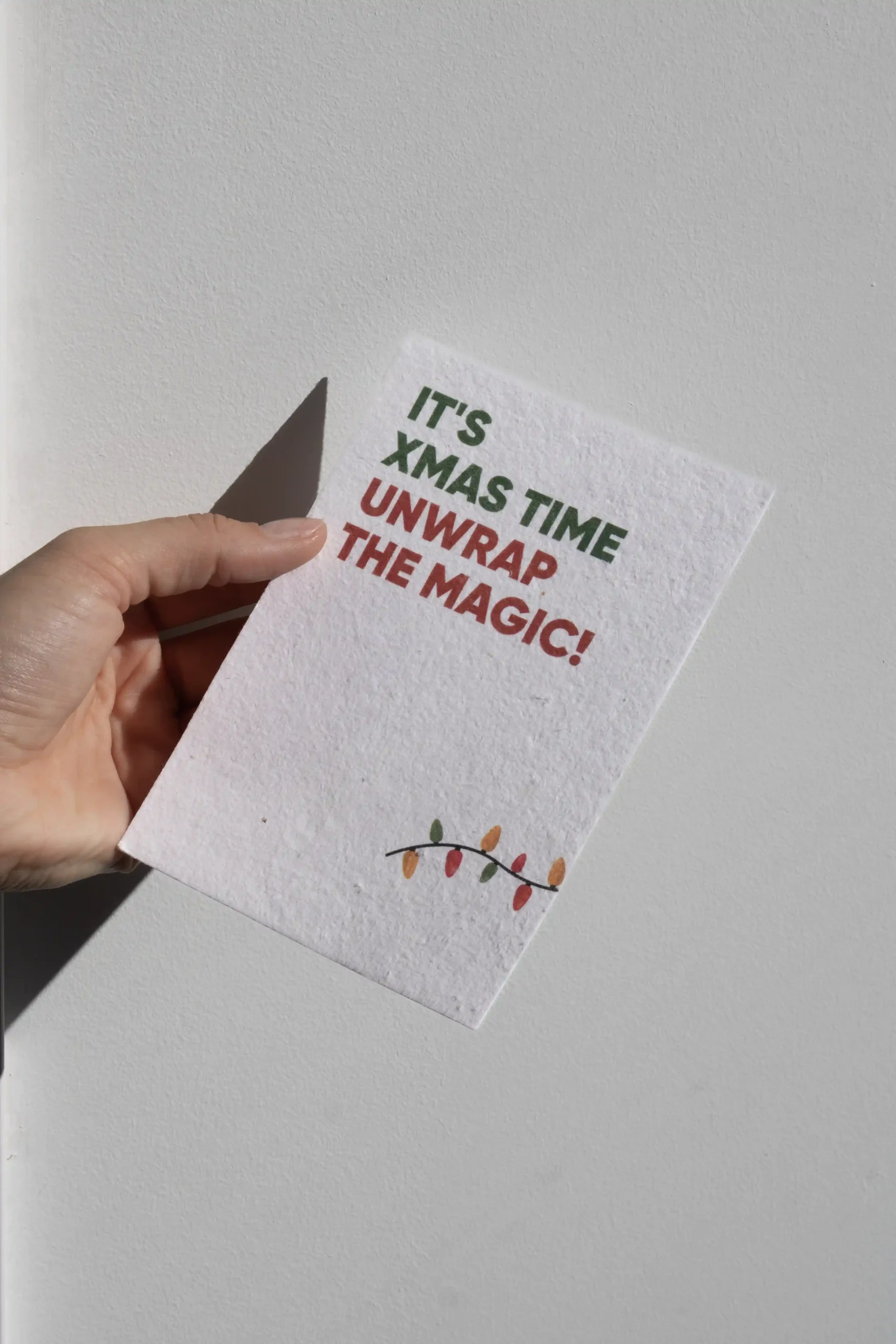 Manos sujetando una tarjeta de Navidad personalizada con fondo blanco