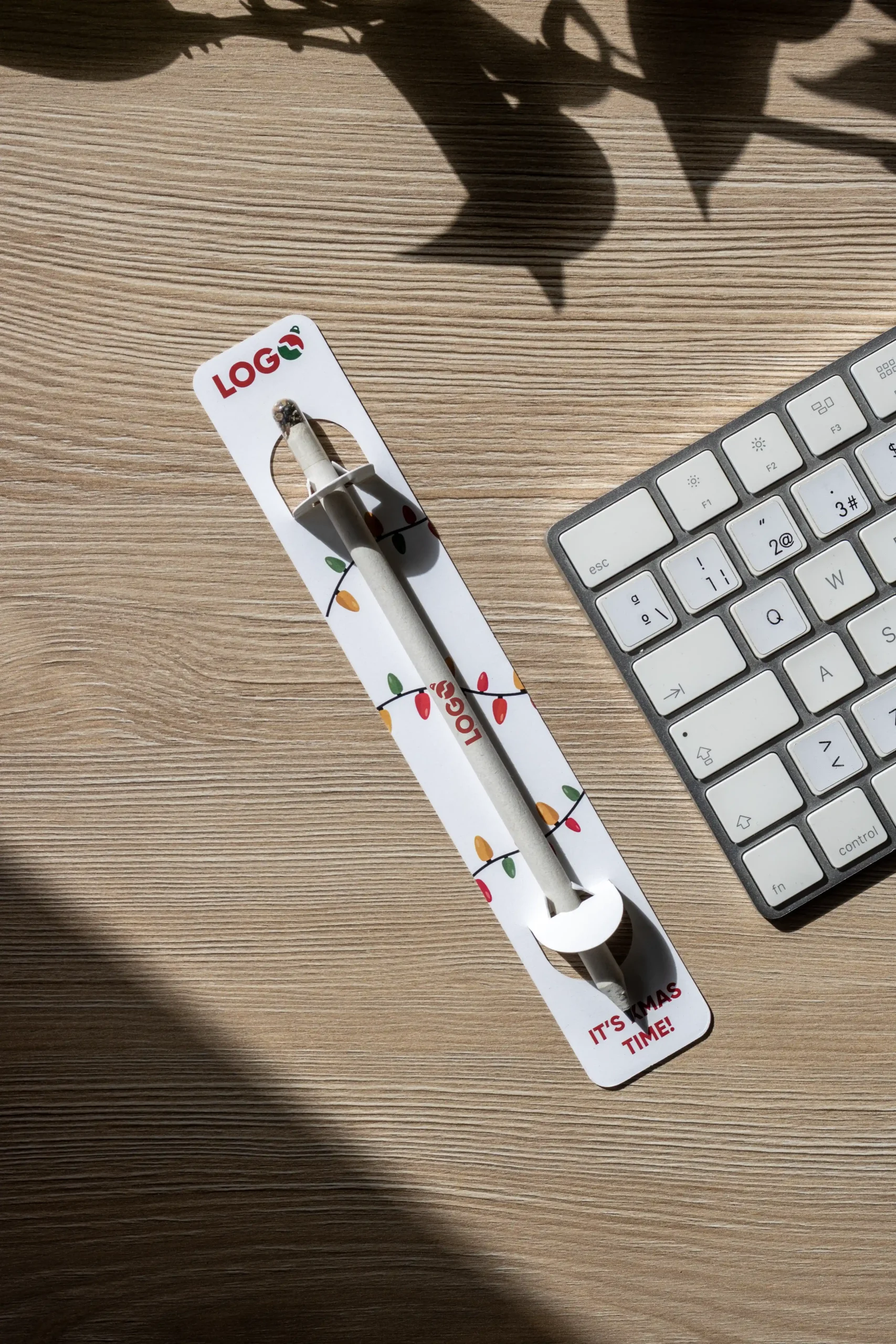 Lápiz plantable personalizado con diseño de Navidad sobre una mesa de madera de trabajo coon un teclado de ordenador