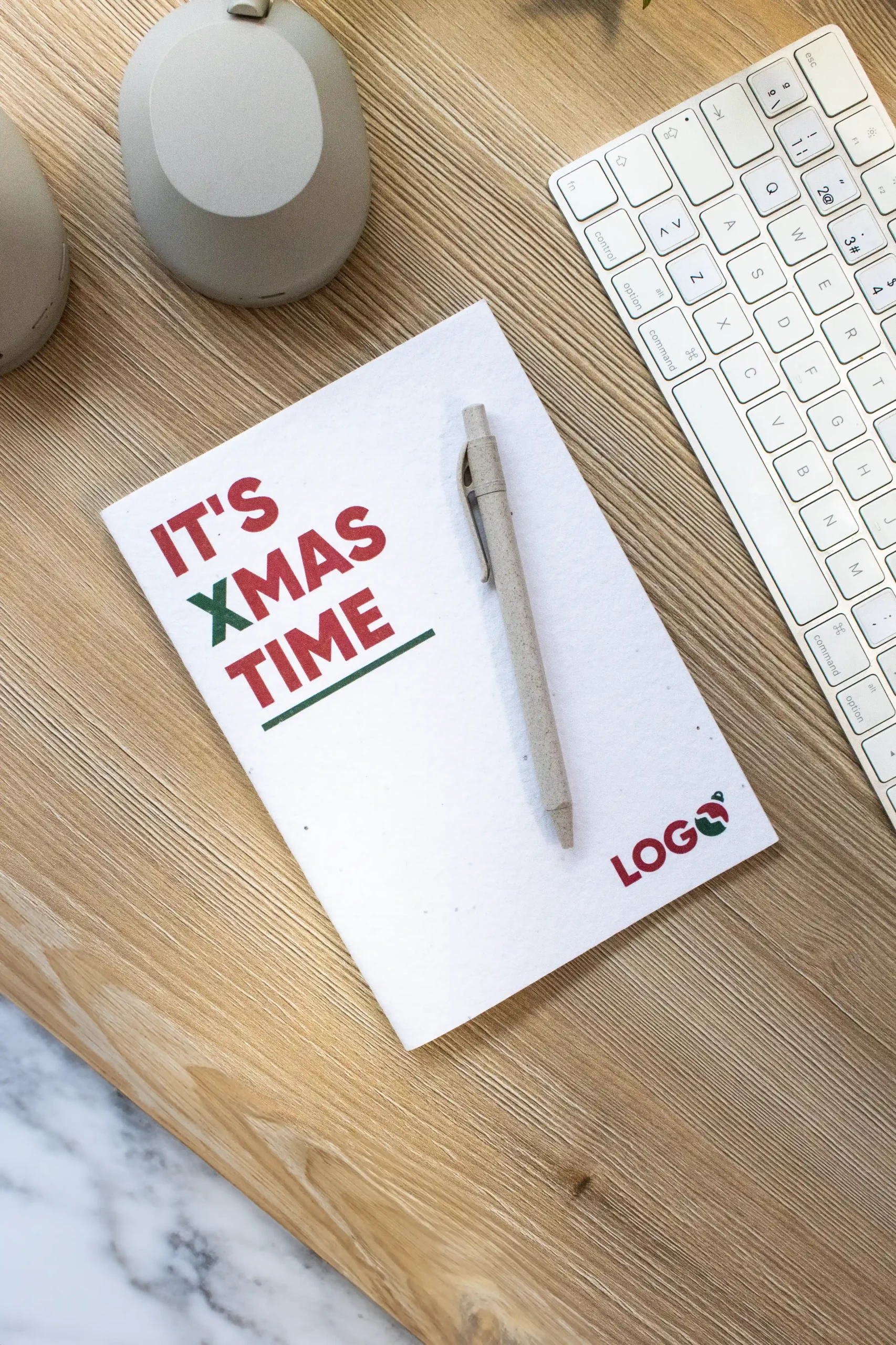 Cuaderno plantable personalizado con diseño de Navidad sobre una mesa de madera de trabajo con un bolígrafo y un teclado de ordenador
