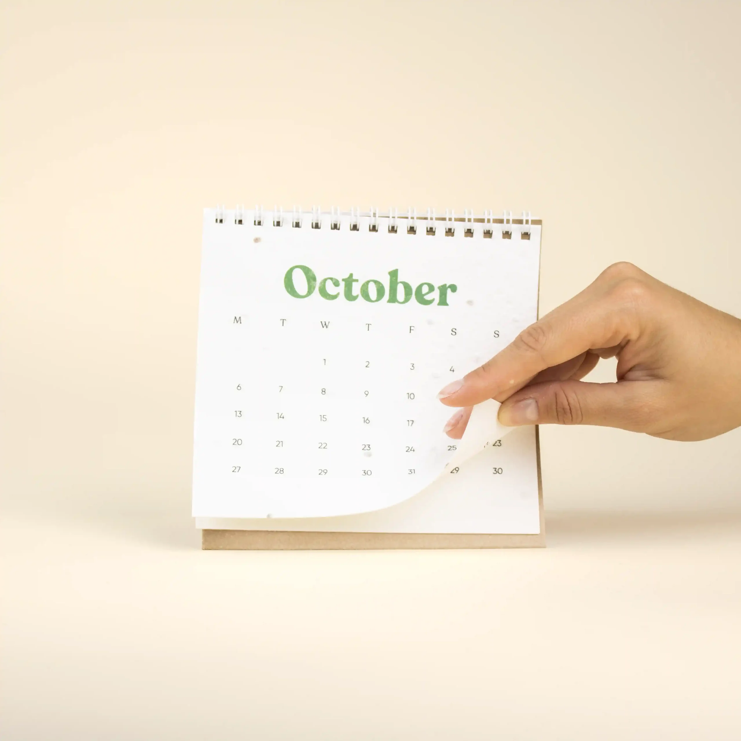 Mano pasando la hoja de octubre de una calendario plantable de mesa