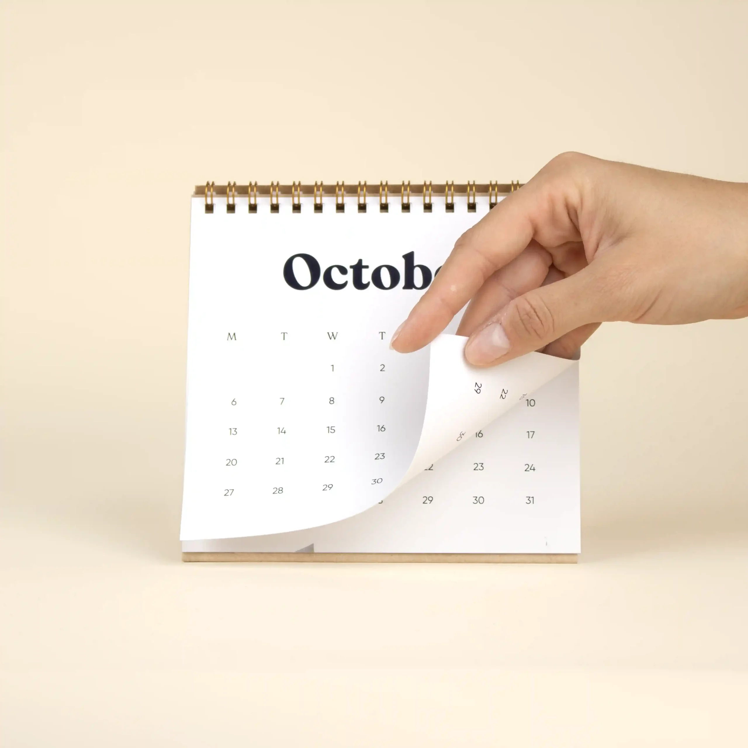 Mano pasando la hoja del mes de Octubre de un calendario triangular de mesa personalizado