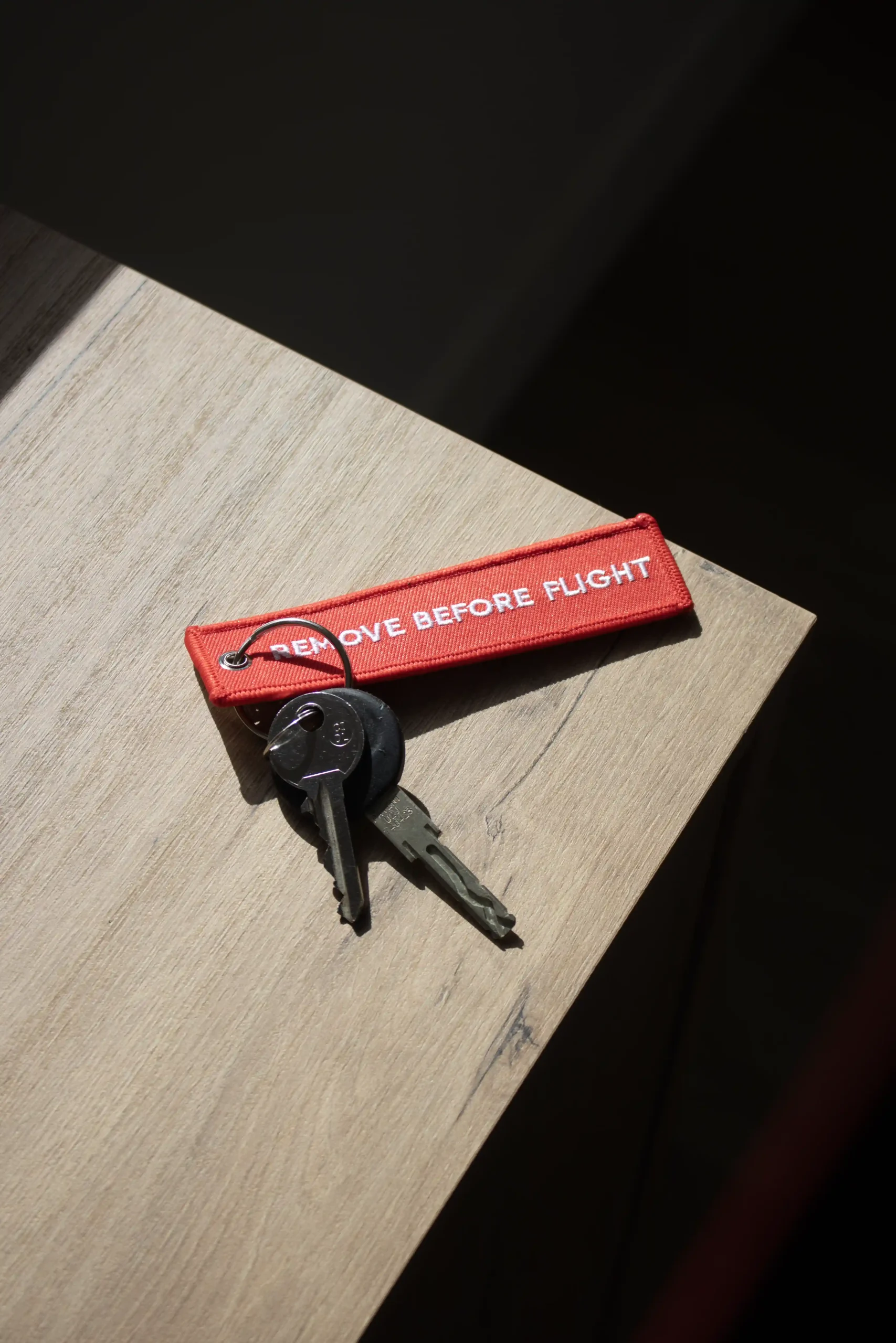 Llaves con llavero de tela rojo personalizado bordado con hilo blanco sobre una mesa de madera