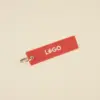 Llavero de tela rojo personalizado bordado con hilo blanco sobre fondo beige