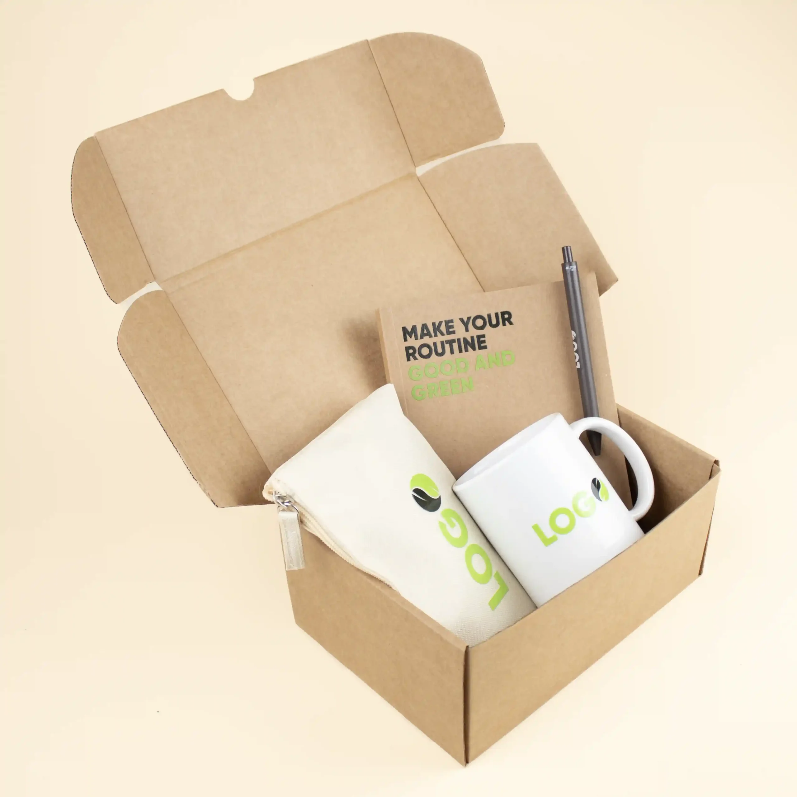 Caja de cartón abierta con un neceser beige, una taza blanca, un cuaderno kraft y un bolígrafo marrón personalizados con logo