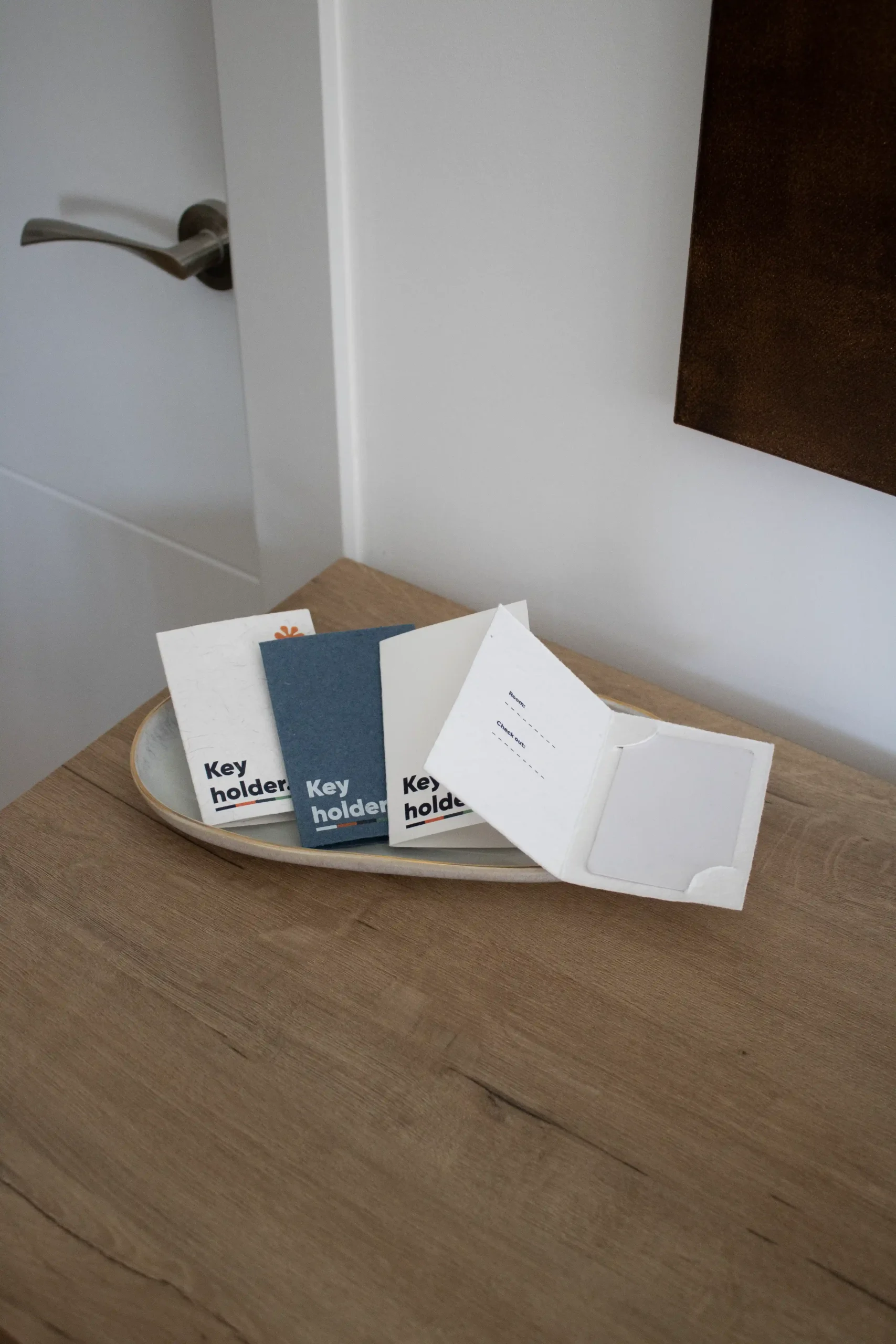 4 porta llaves de hotel personalizados colocados en una bandeja sobre una mesa de madera