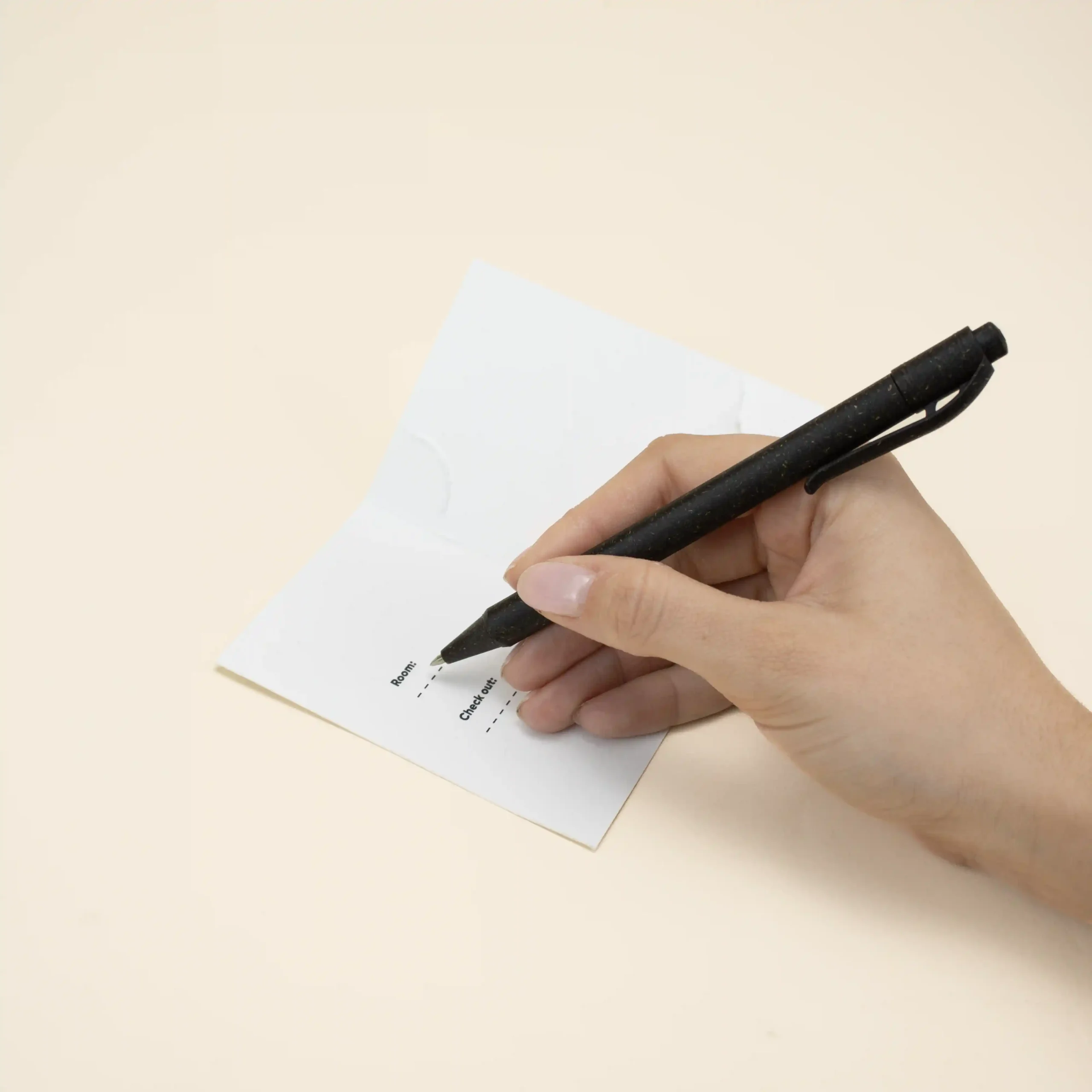 mano escribiendo con un bolígrafo en un porta llaves de hotel blanco abierto