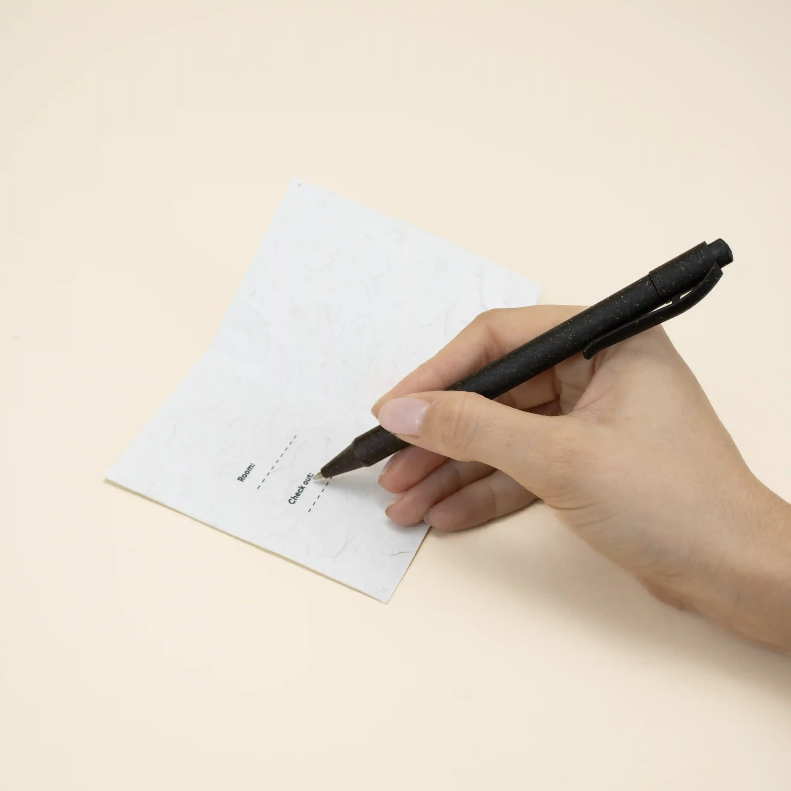 mano escribiendo con un bolígrafo en un porta llaves de hotel blanco personalizado con la palabra logo en azul