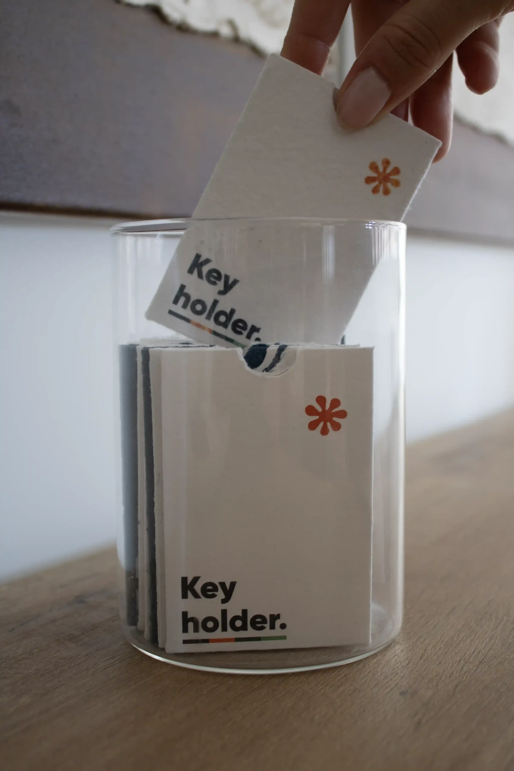 Mano metiendo un porta llaves de hotel personalizado en un jarrón de cristal transparente