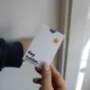 Mano mostrando un porta llaves de hotel en papel ecológico blanco personalizado con la palabra key holder en azul antes de abrir la puerta