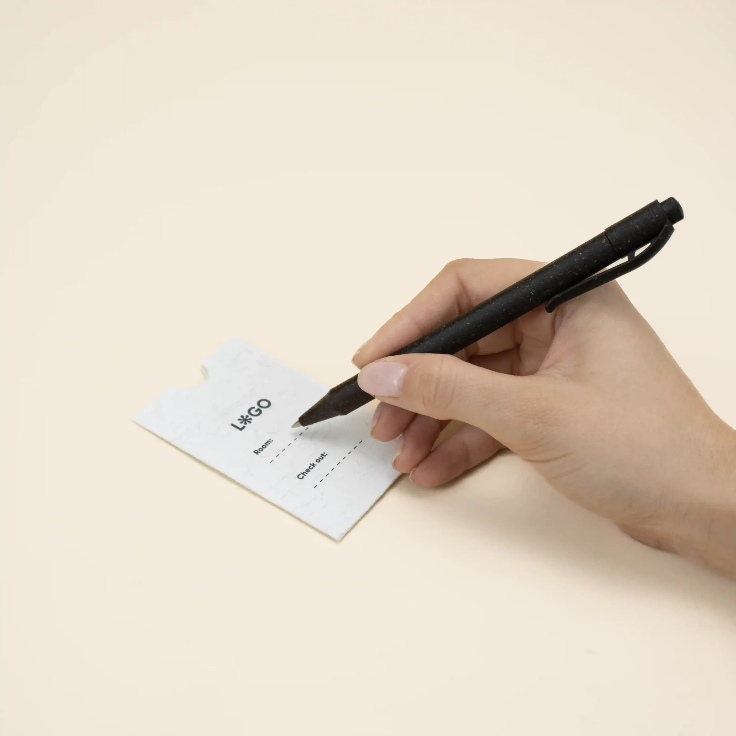mano escribiendo con un bolígrafo en un porta llaves de hotel blanco personalizado con la palabra logo en azul