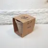 Kit plantable de fibra de coco dentro de un packaging en cartón kraft personalizado delante de un cojín blanco