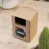 Kit plantable de barro dentro de un packaging en cartón kraft personalizado con una pegatina sobre una mesa de madera