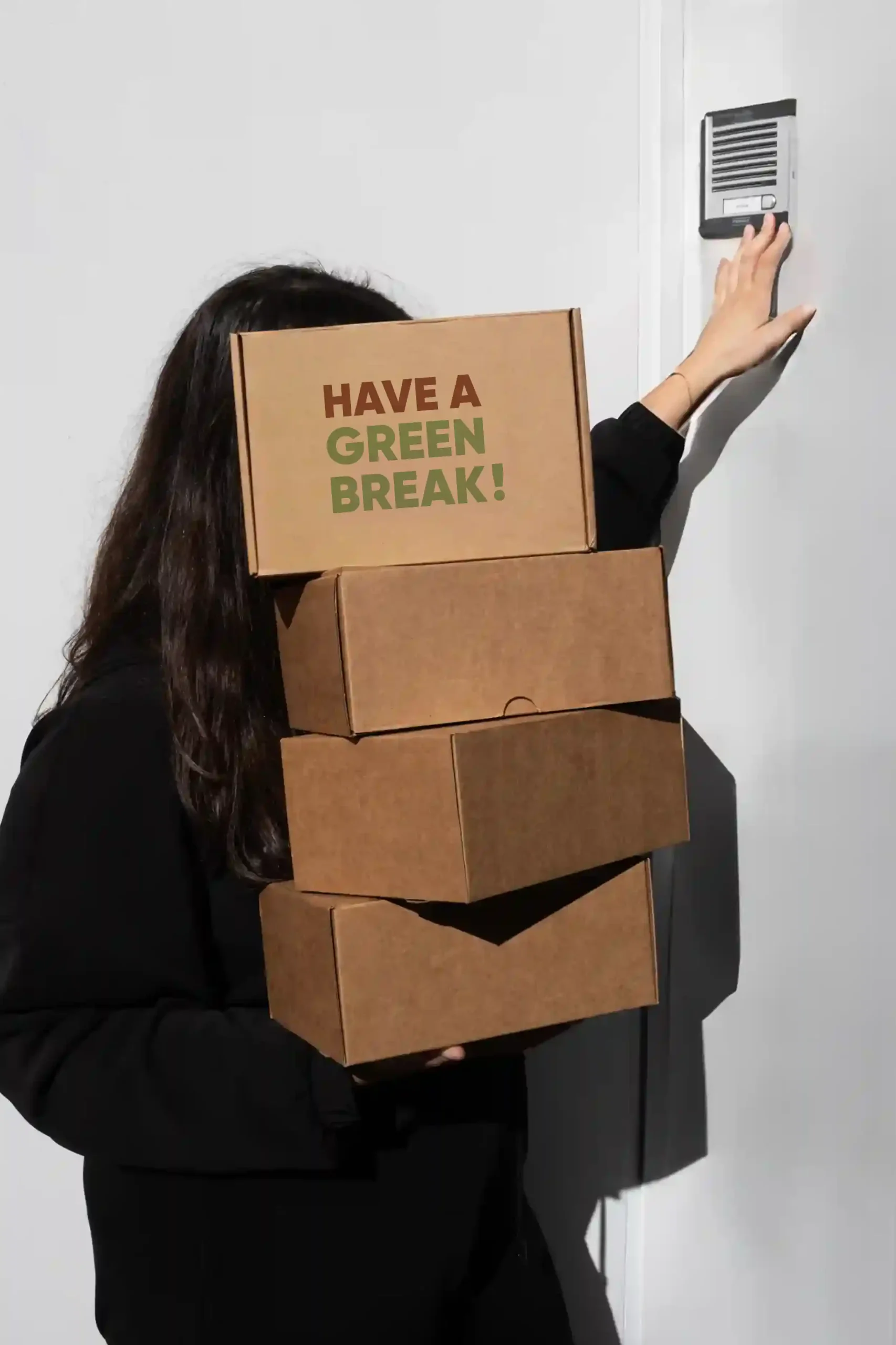 Chica cargando cajas de cartón personalizadas con el texto 'have a green break'
