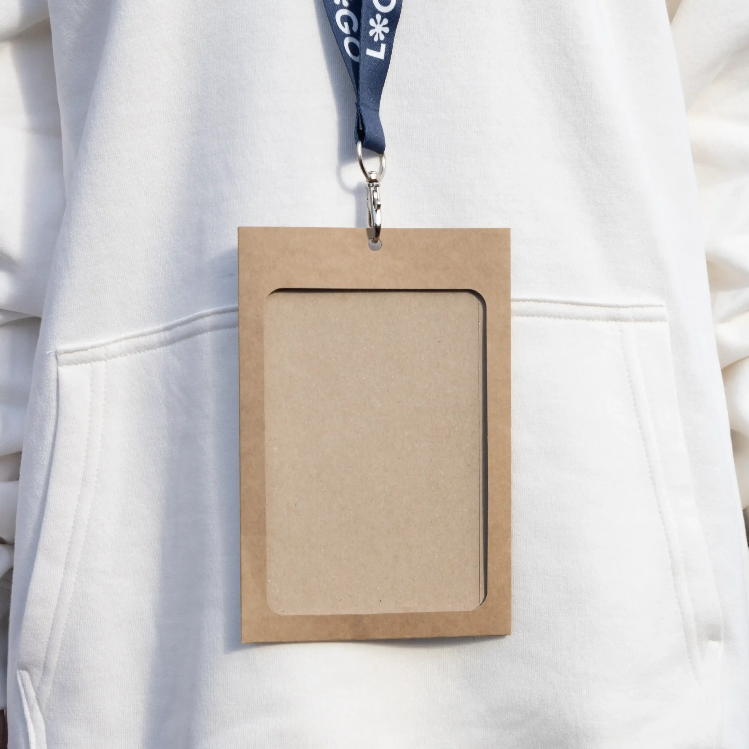 Funda de acreditación kraft y lanyard de rPET azul personalizado colgado del cuello de una persona con jersey blanco