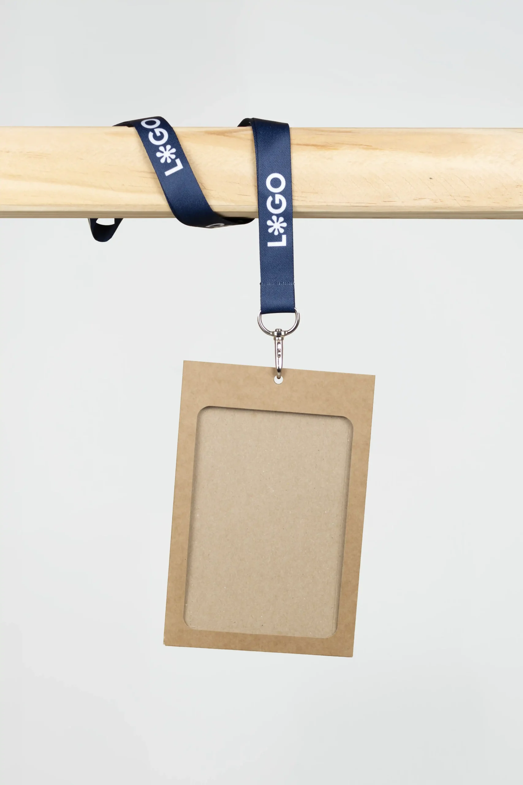 Funda de acreditación kraft con lanyard de rPET azul personalizado con el texto 'logo' en blanco colgada de una barra de madera