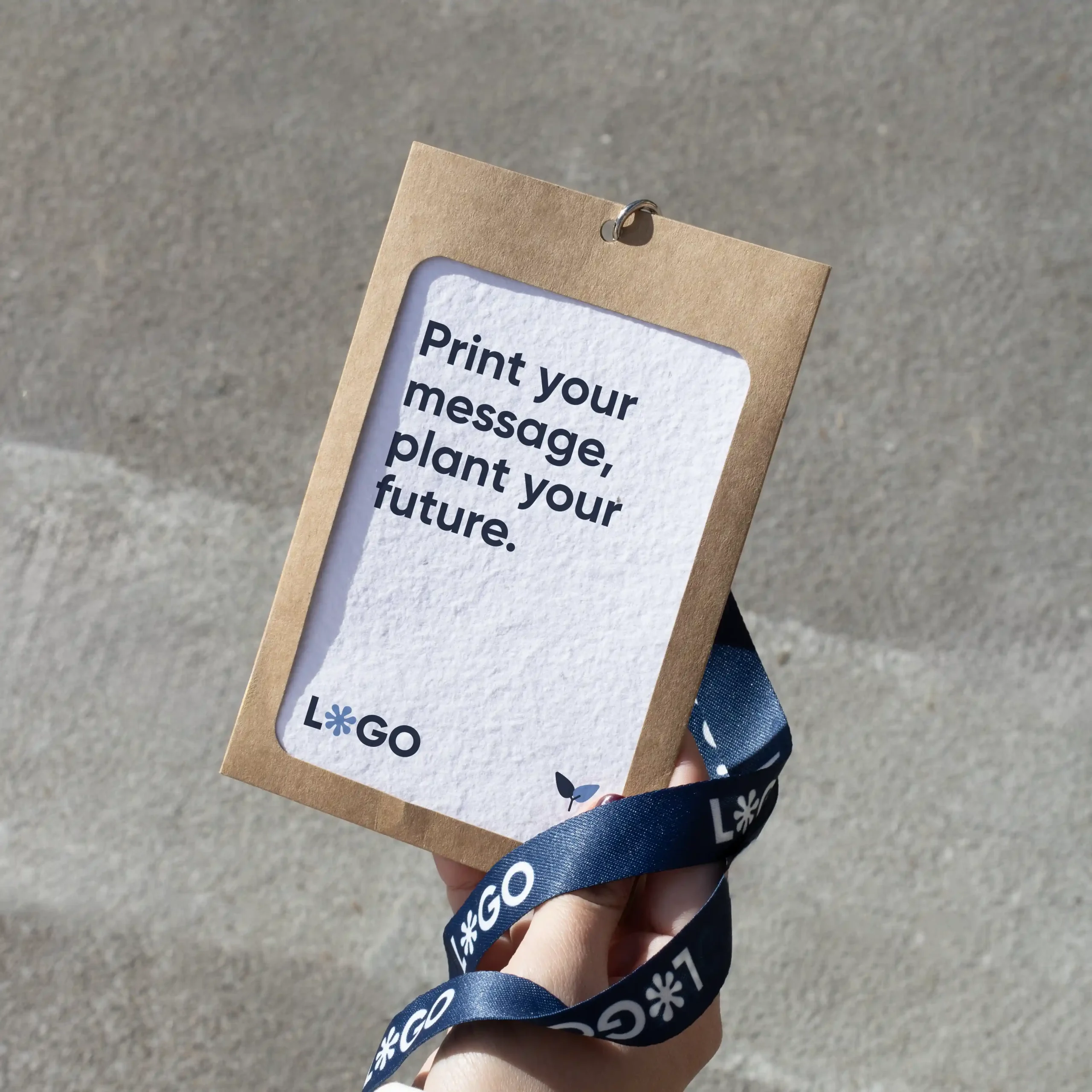 Mano sujetando una acreditación personalizada con funda kraft y lanyard de rPET azul personalizado con el texto 'logo' en blanco