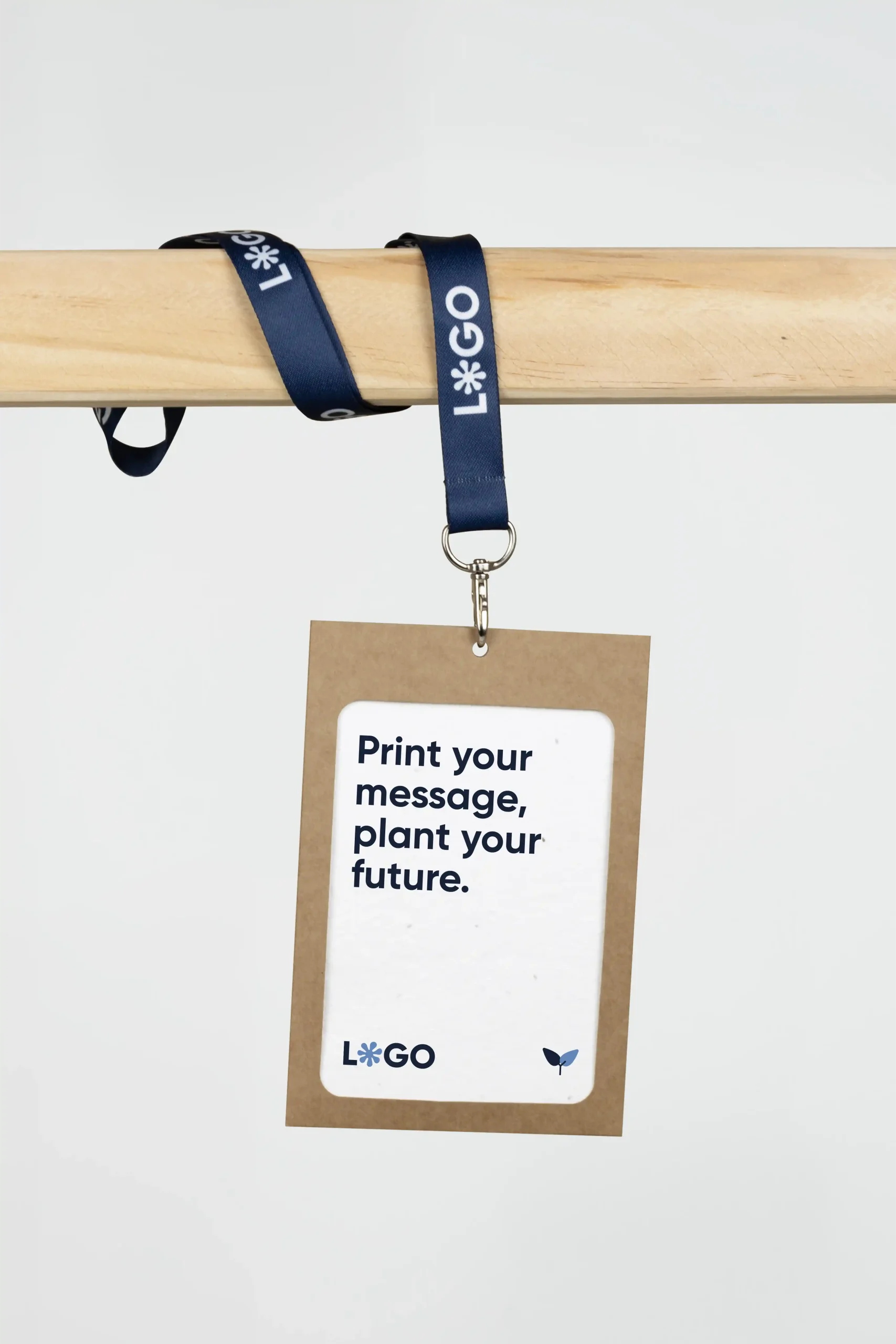 Acreditación personalizada con funda kraft y lanyard de rPET azul personalizado con el texto 'logo' en blanco colgada de una barra de madera