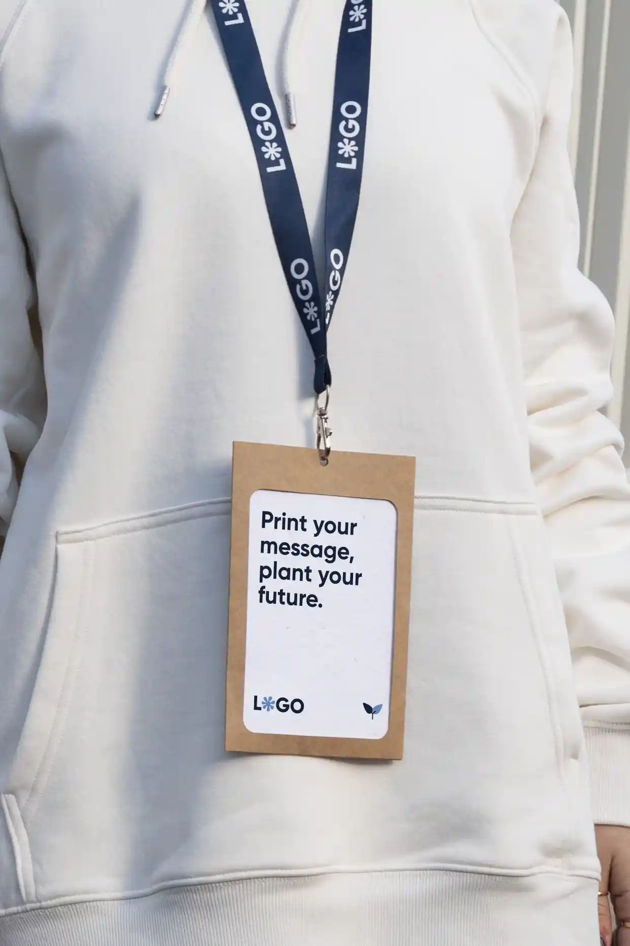 Acreditación personalizada con funda kraft y lanyard de rPET azul personalizado con el texto 'logo' en blanco colgado del cuello de una persona con jersey blanco