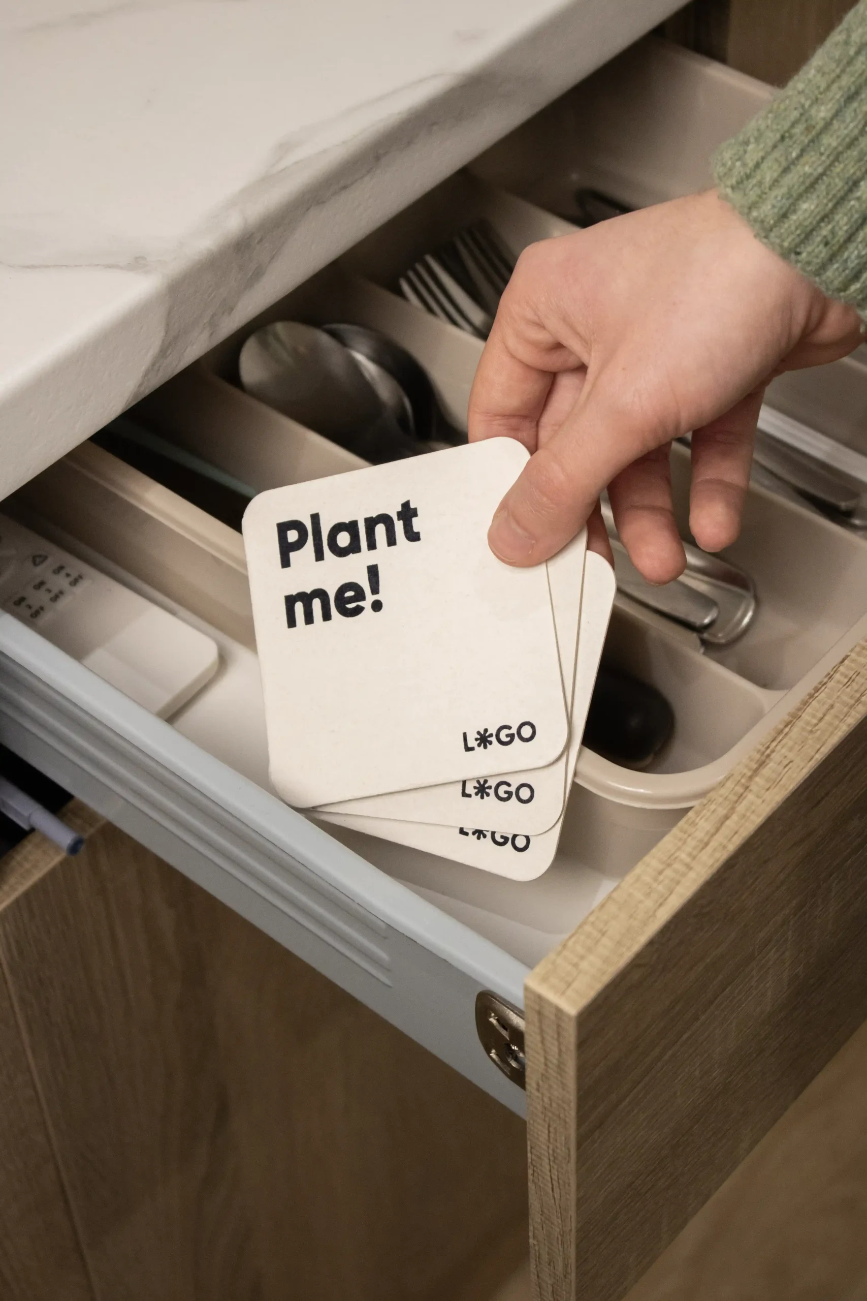 Mano guardando unos posavasos de cartón personalizados en un cajón de cubiertos