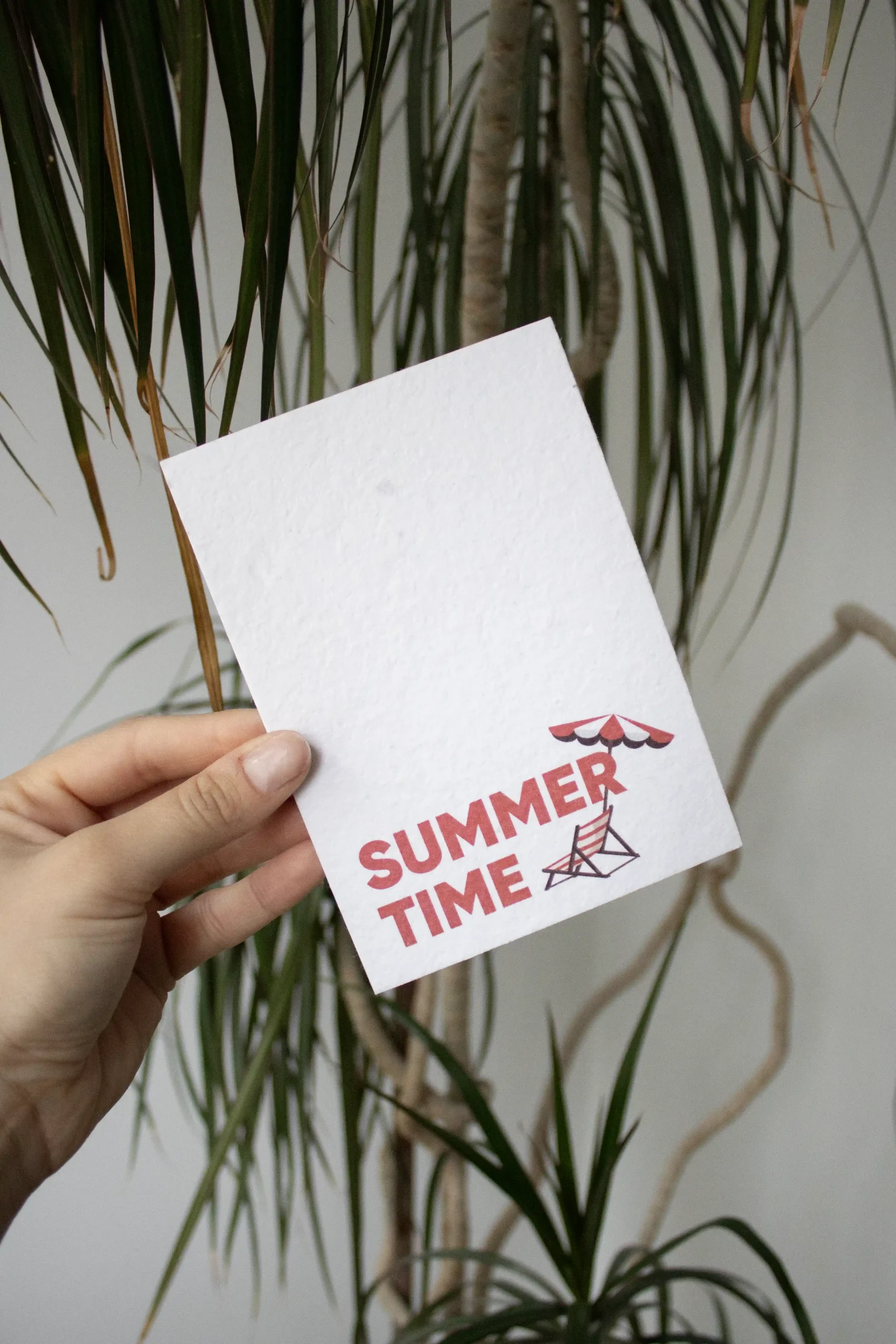 Mano mostrando una tarjeta A6 de papel personalizada con el texto 'summer time' en rojo