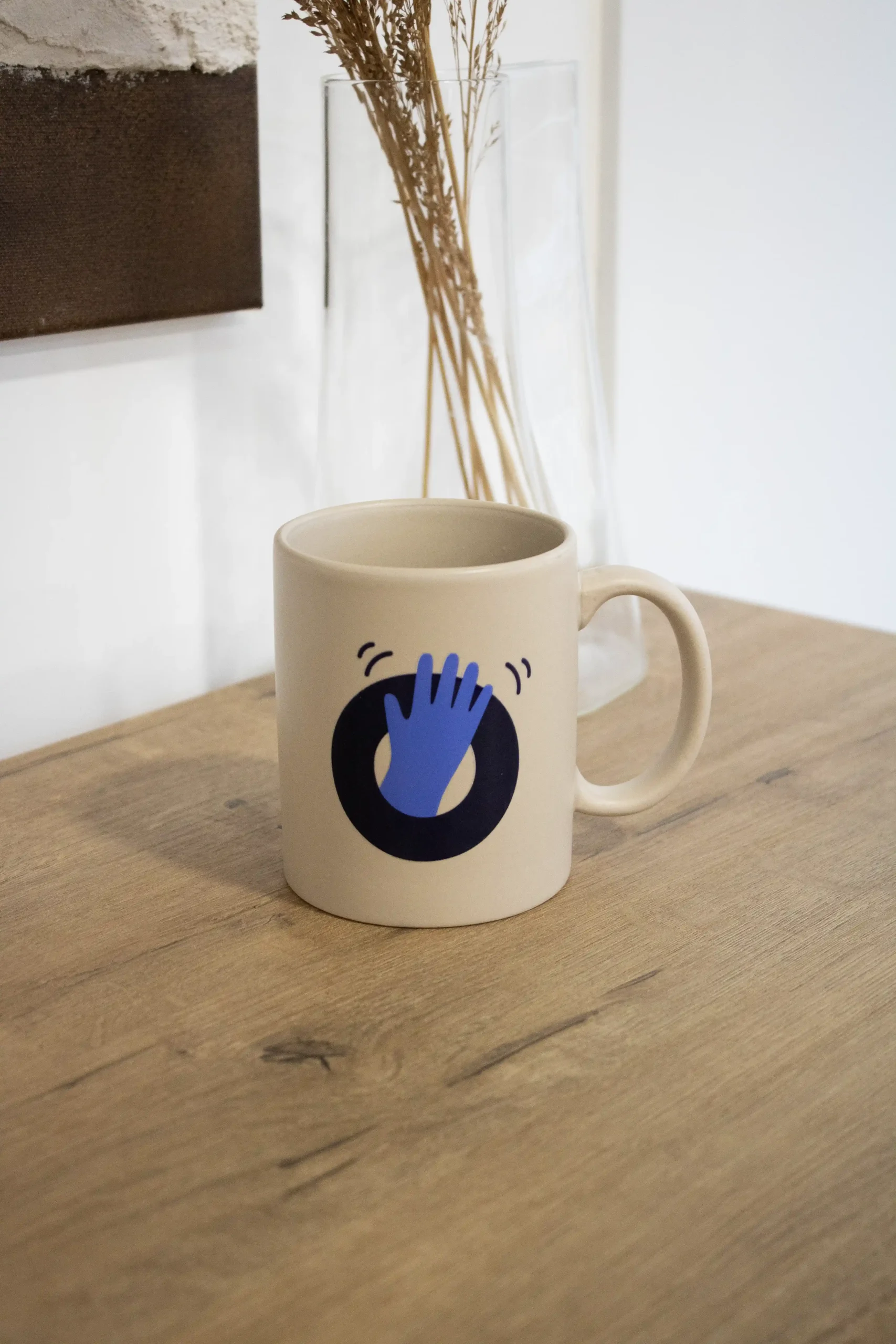 Taza de cerámica beige personalizada con una ilustración en color azul sobre una superficie de madera