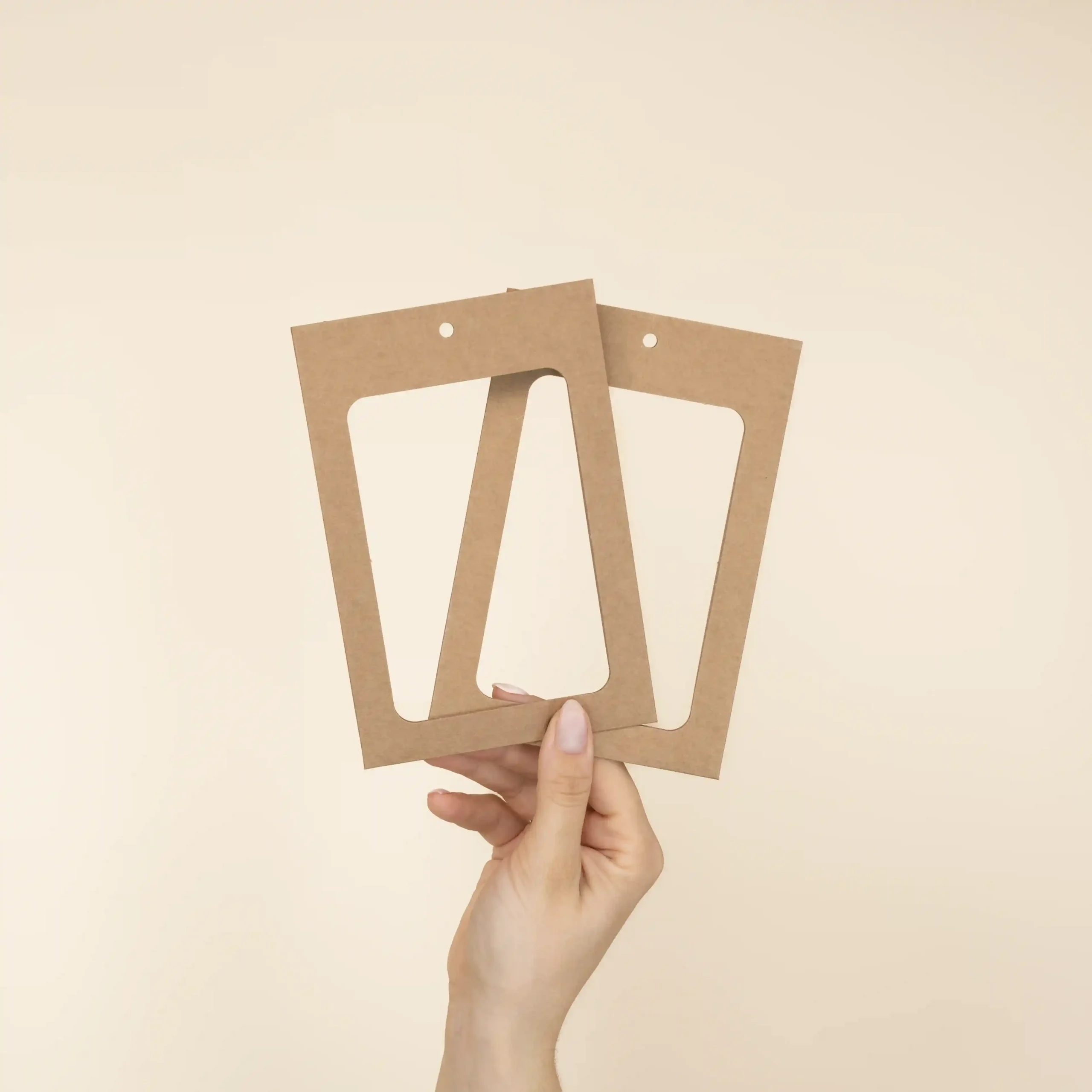 Mano mostrando dos fundas de acreditación en cartón kraft marrón