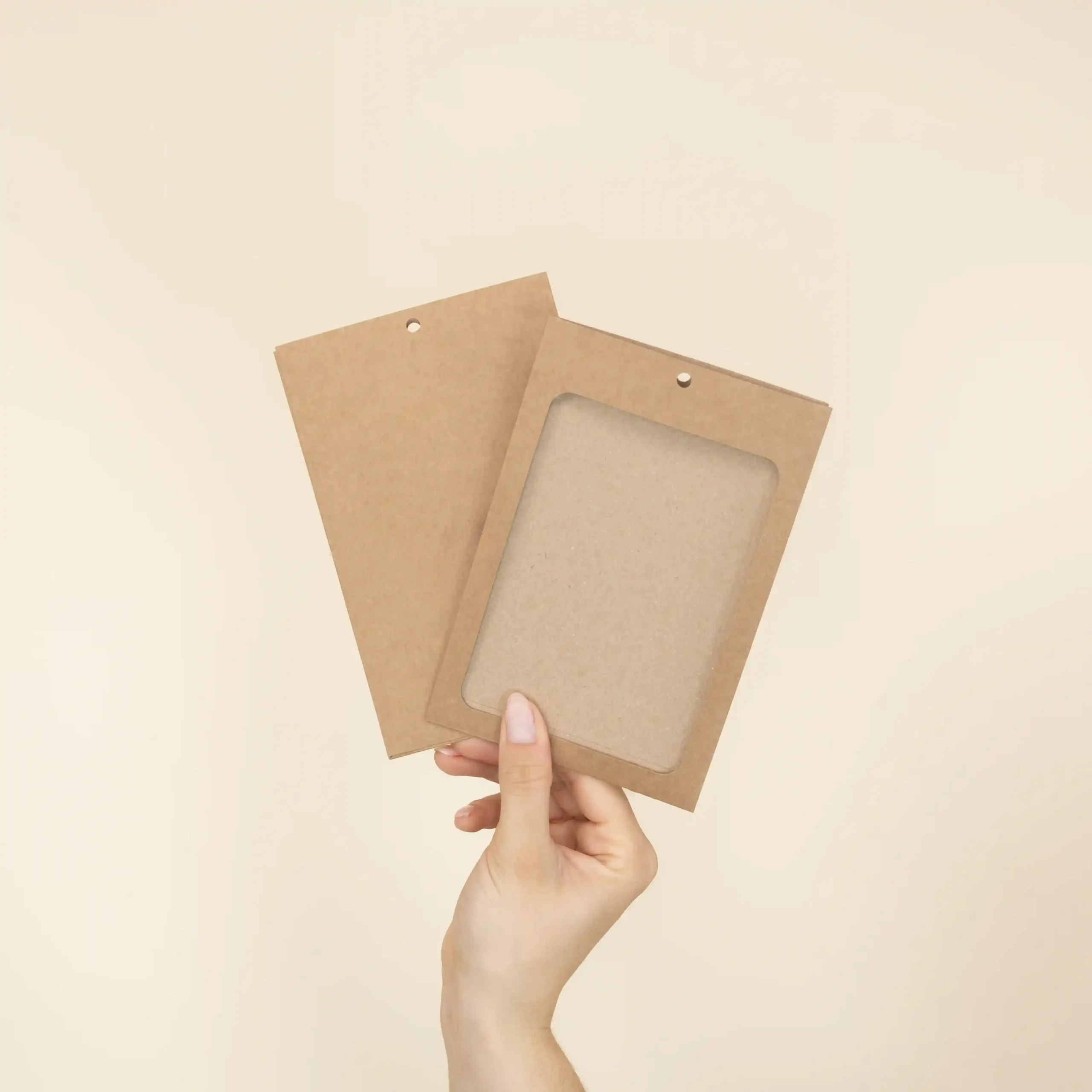 Mano mostrando dos fundas de acreditación en cartón kraft marrón