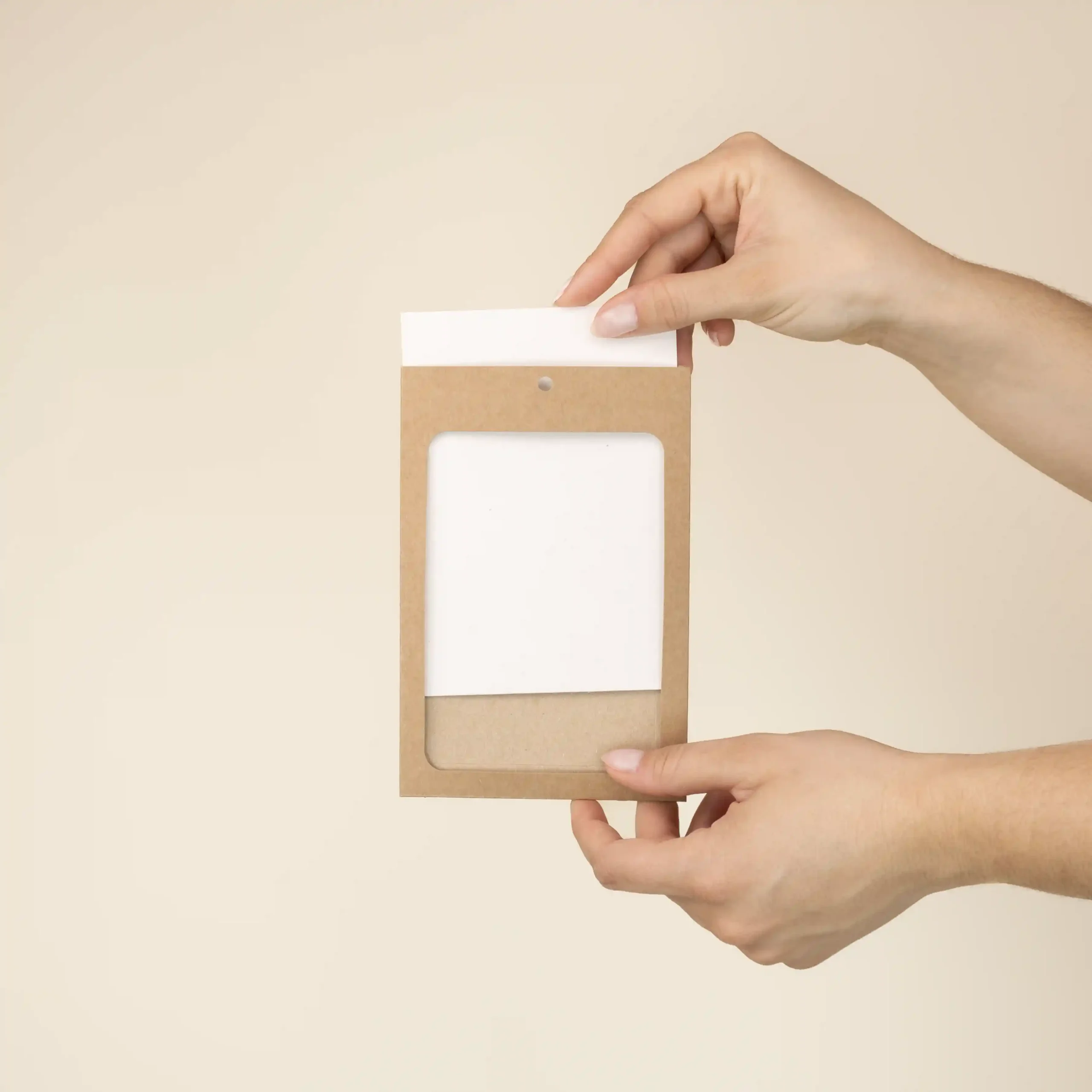 Dos manos metiendo una acreditación de papel blanco en una funda de cartón kraft marrón