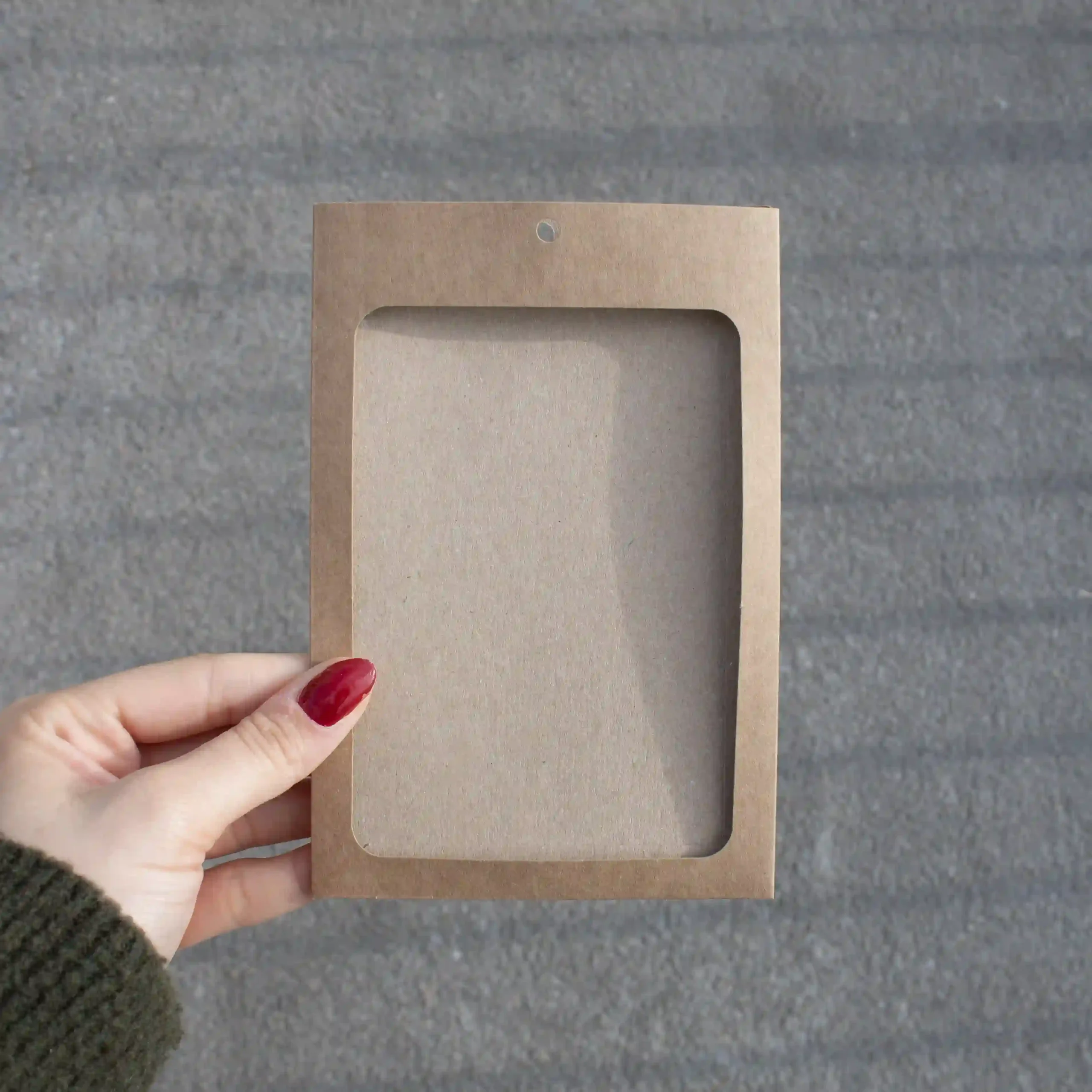 Mano mostrando una funda de acreditación en cartón kraft marrón