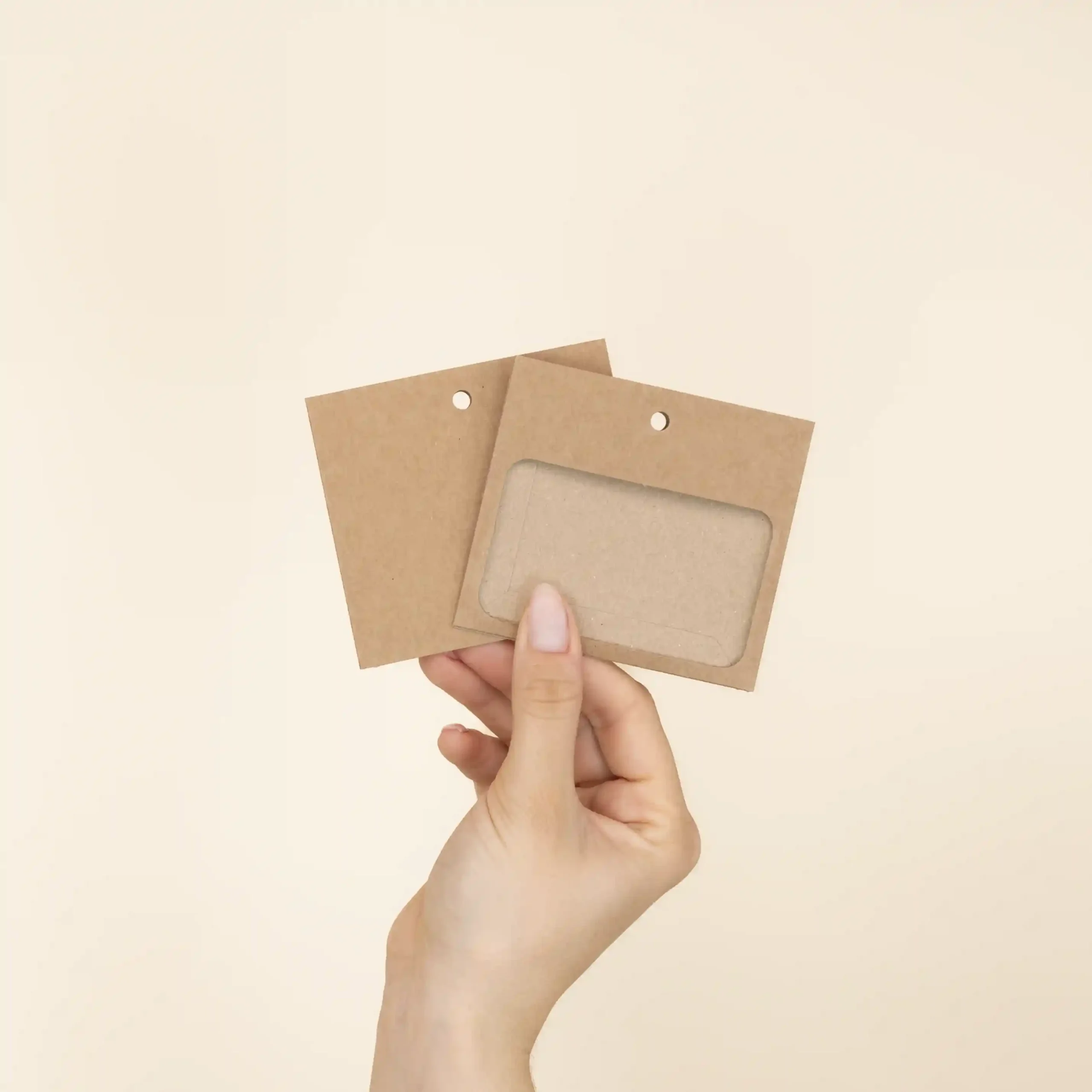 Mano mostrando dos fundas de acreditación en cartón kraft marrón
