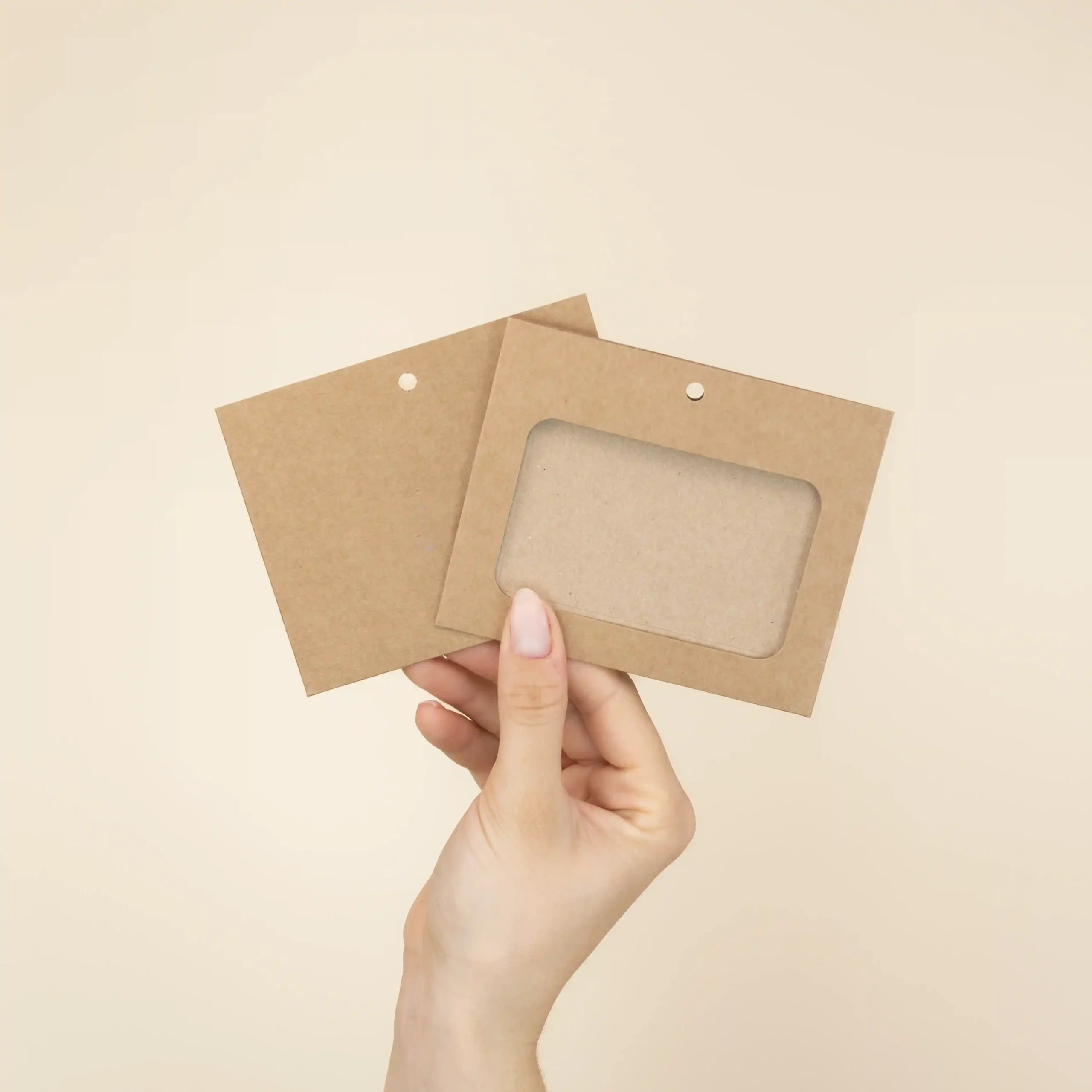 Mano mostrando dos fundas de acreditación en cartón kraft marrón