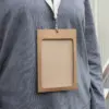 Funda acreditación KASE 4/0, A6 (13x9 cm) Funda de acreditación de cartón kraft marrón colgada de un lanyard de algodón blanco colocado en el cuello de una persona