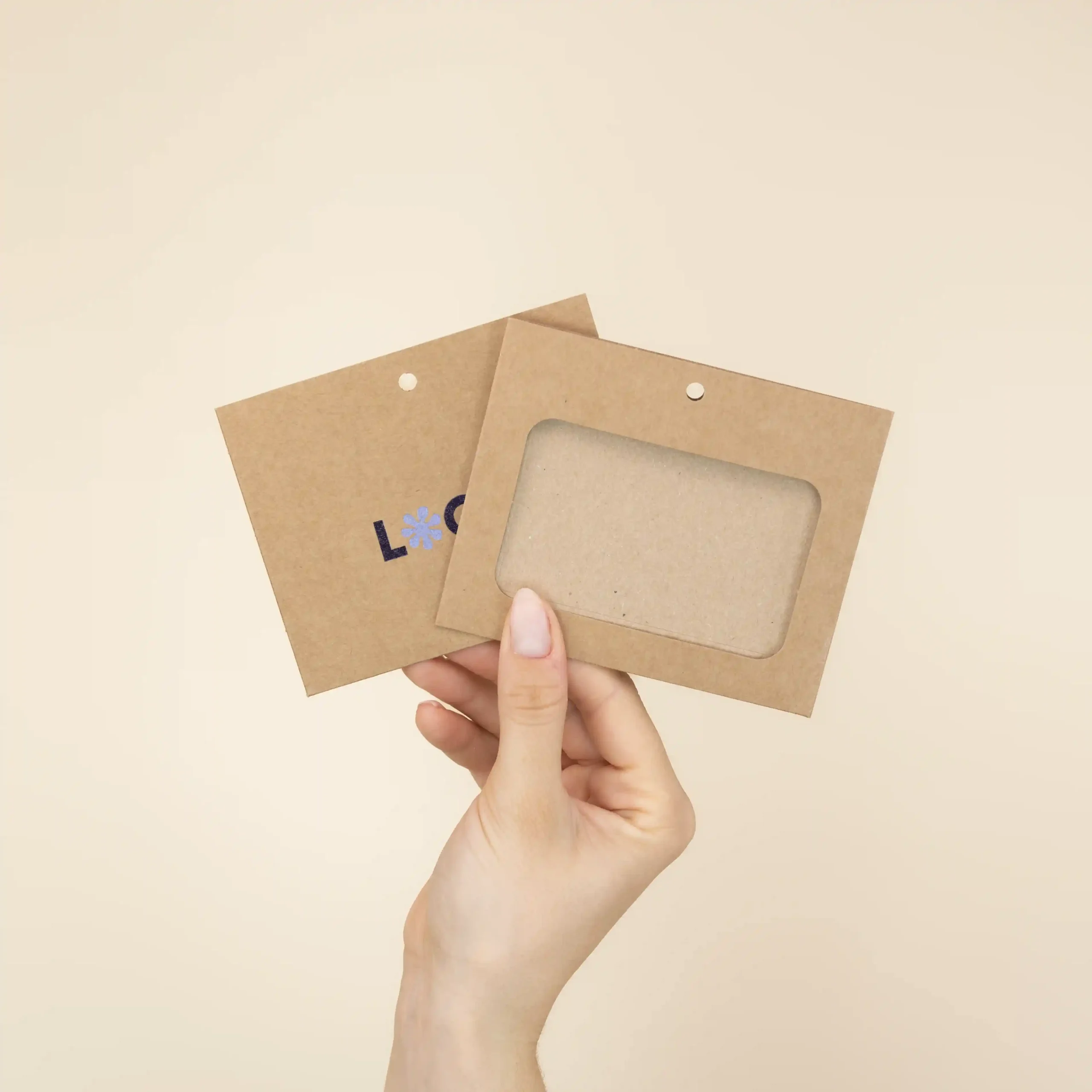 Mano mostrando dos fundas de acreditación en cartón kraft marrón