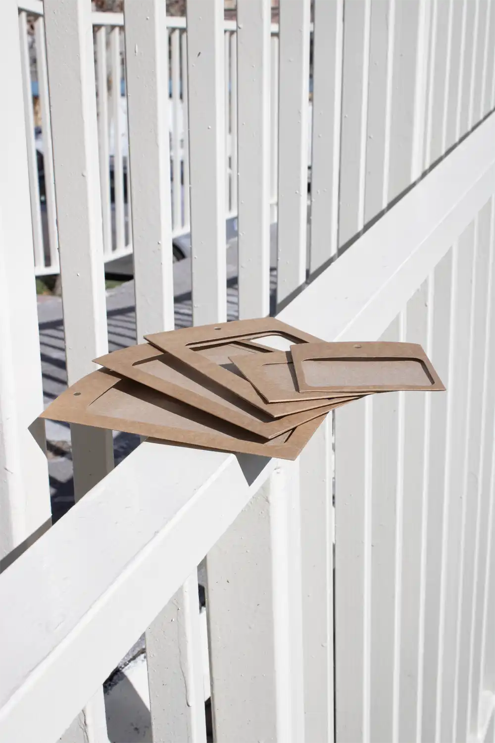 Fundas de acreditación en cartón kraft marrón apoyadas en una barandilla blanca