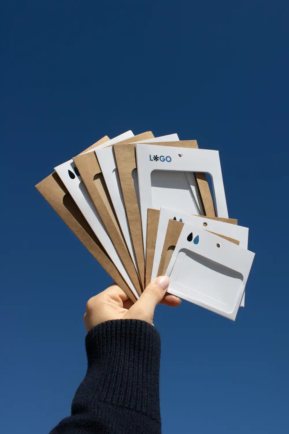 Mano mostrando un conjunto de fundas de acreditación personalizadas en forma de abanico con el cielo de fondo