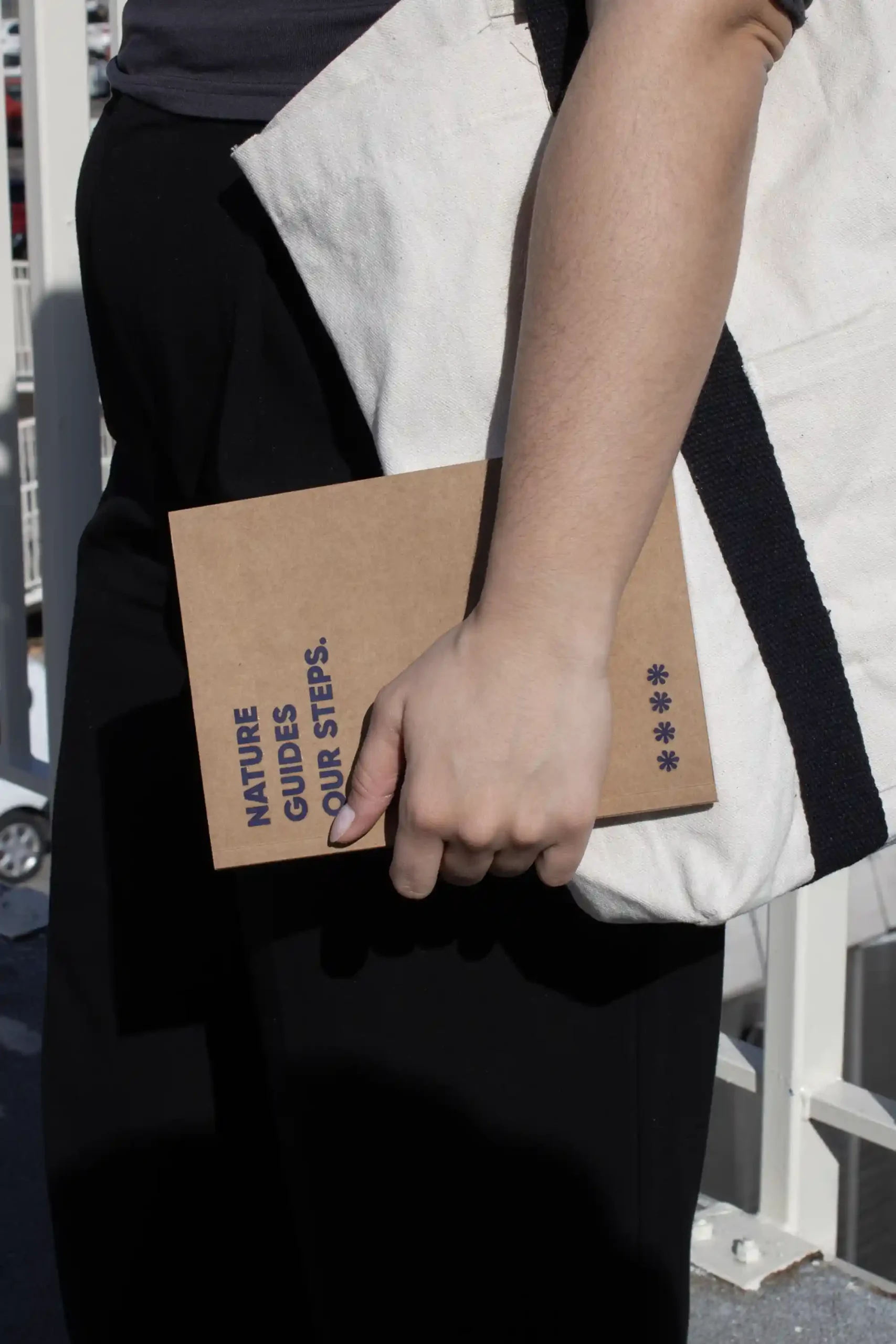 Chica llevando en la mano un cuaderno plantable kraft personalizado con el texto 'Nature guides our steps'