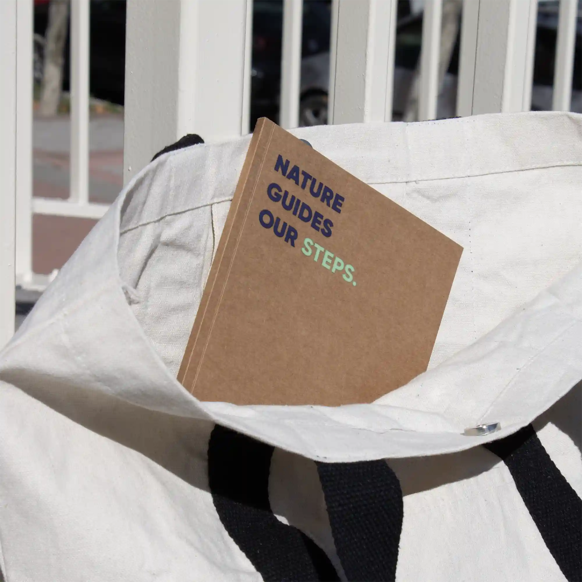 Cuaderno plantable kraft personalizado con el texto 'Nature guides our steps' dentro de una bolsa de algodón blanca